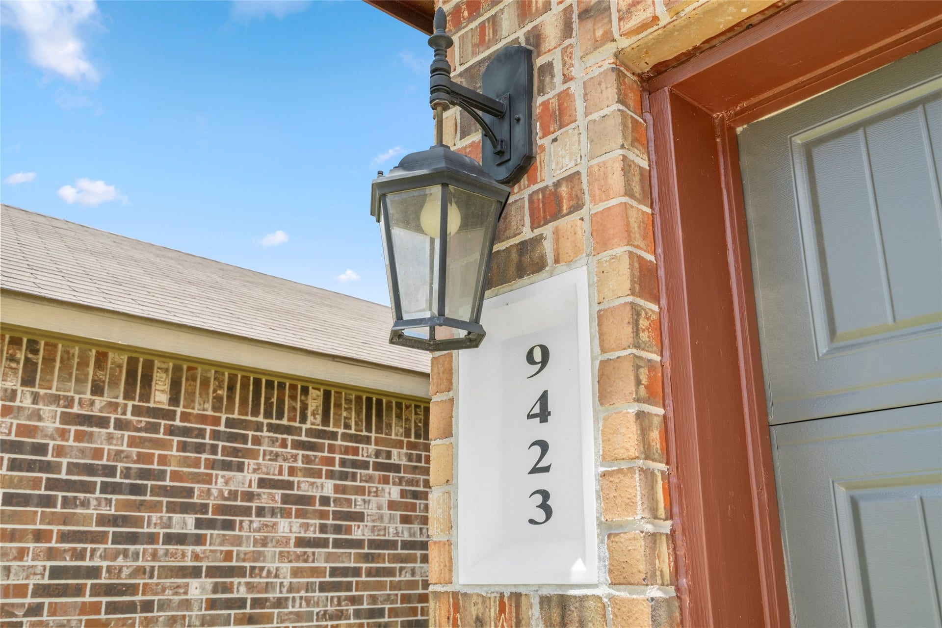 9423 Mineral Rock Lane, Richmond, TX 77407 Classic lantern lighting and bold address numbers add timeless charm to the brick facade.