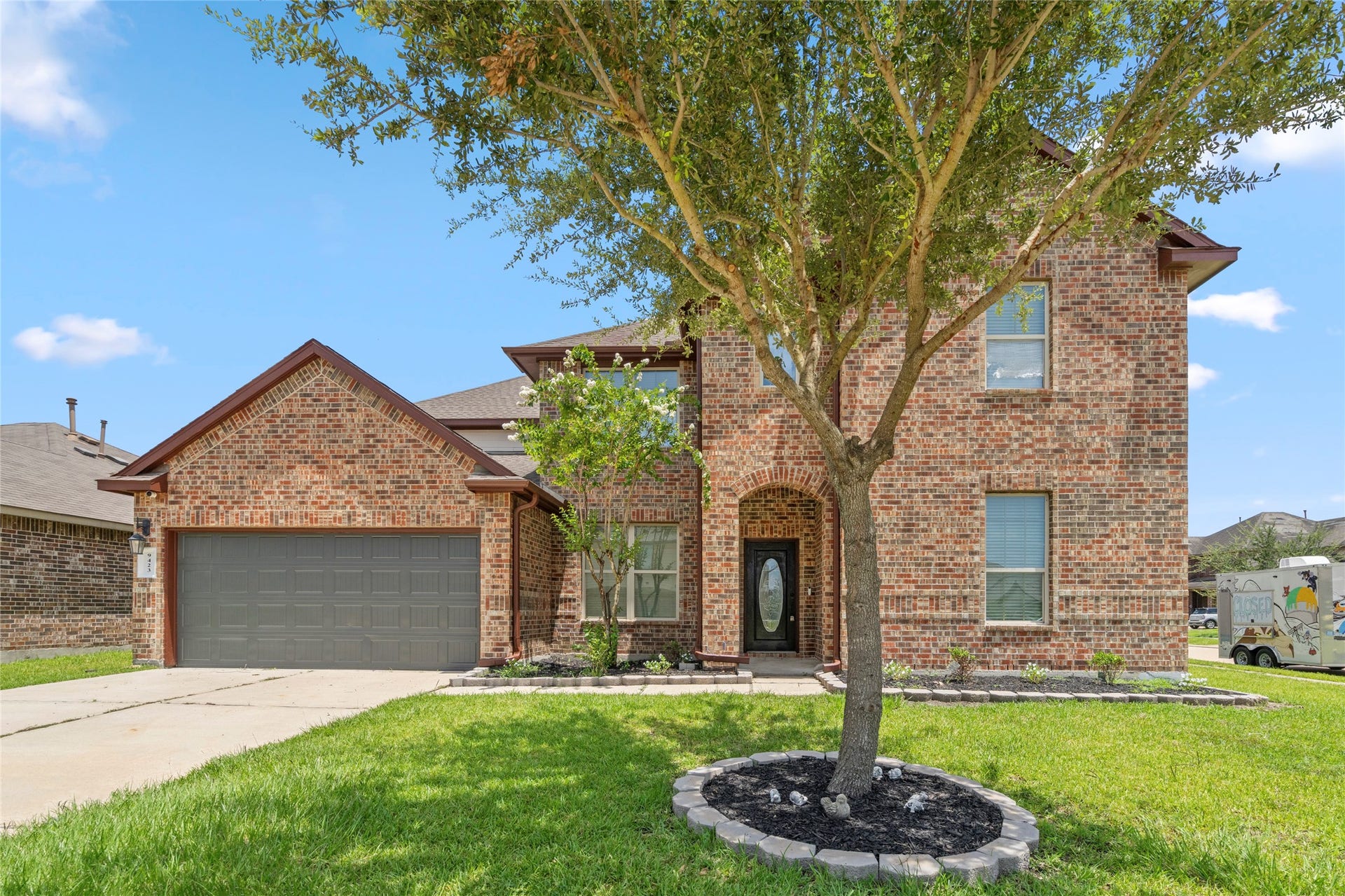 9423 Mineral Rock Lane, Richmond, TX 77407 An arched entryway framed by mature trees leads to a striking glass-paneled front door a graceful welcome home.