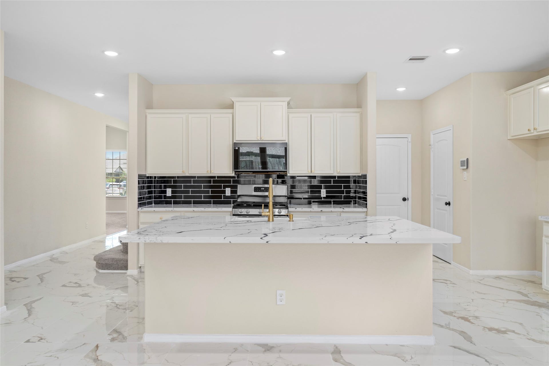 9423 Mineral Rock Lane, Richmond, TX 77407 A modern kitchen featuring sleek black subway tiles, elegant marble countertops, and pristine cabinetry, offering both style and functionality.
