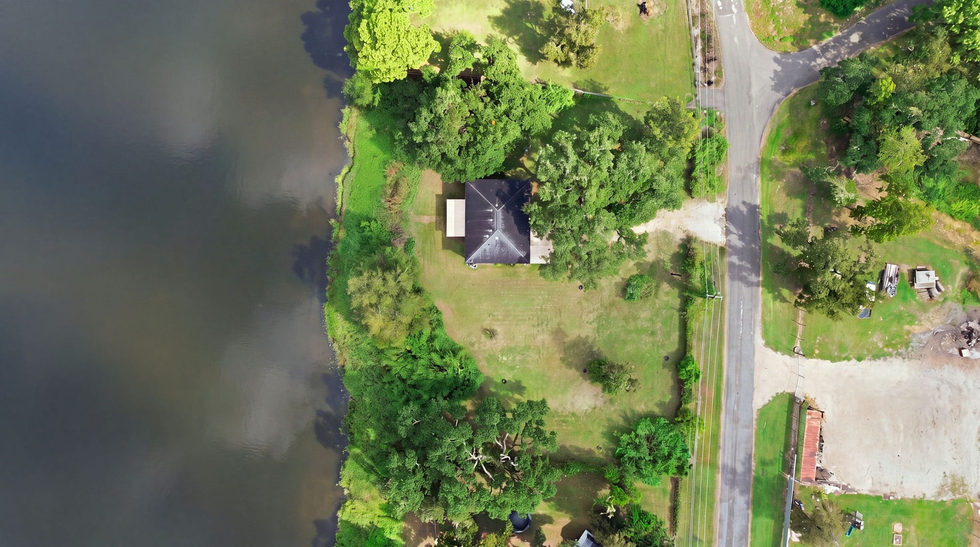 450 N Sunset Boulevard, Holiday Lakes, TX 77515 Aerial view of the property, showing the home's generous lot, mature oak trees, open green lawn, and pond views.