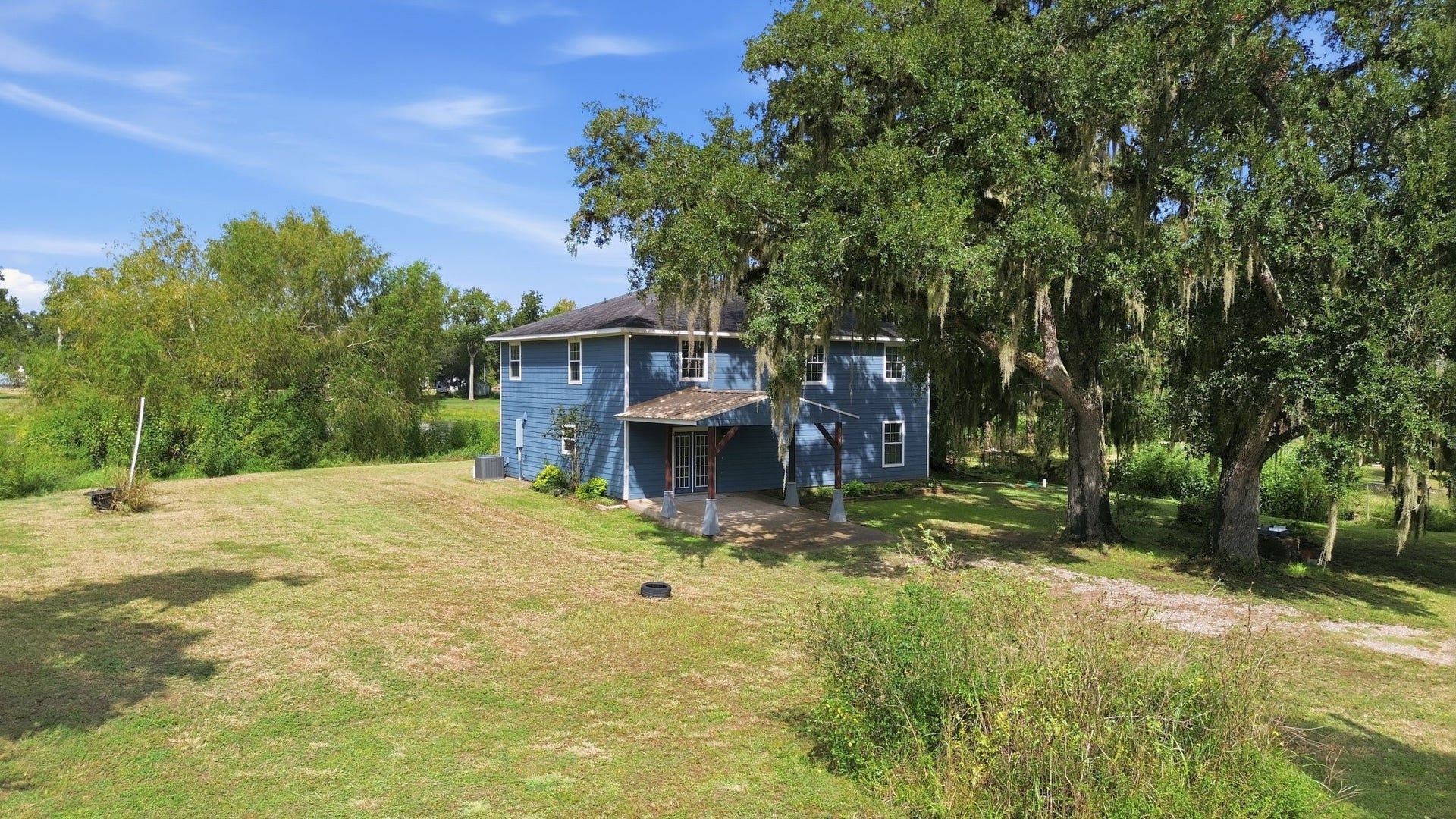 450 N Sunset Boulevard, Holiday Lakes, TX 77515 Front view of the property, surrounded by lush greenery and mature oak trees.