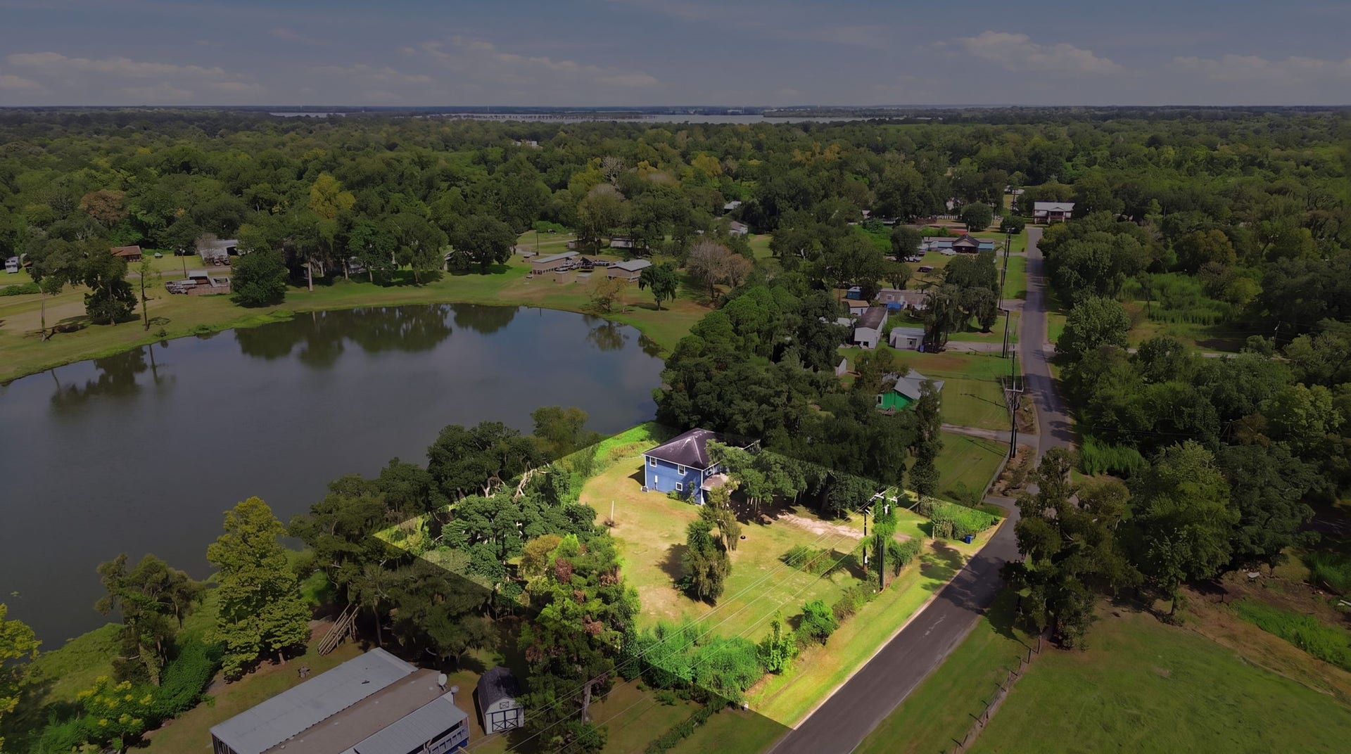 450 N Sunset Boulevard, Holiday Lakes, TX 77515 Expansive aerial view showcasing the propertys generous grounds, mature trees, and peaceful waterfront setting. Enjoy added privacy, open green space, and scenic water views, offering an inviting setting for outdoor living and relaxation.