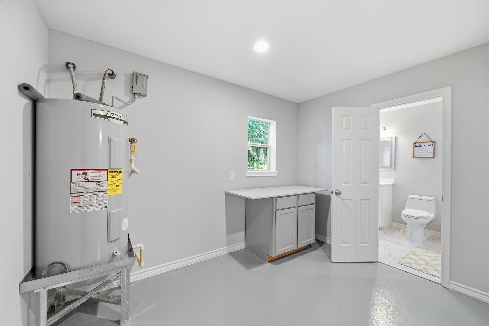 450 N Sunset Boulevard, Holiday Lakes, TX 77515 Laundry room with a folding counter, cabinet storage, and a window for natural light, plus easy access to a half bath.