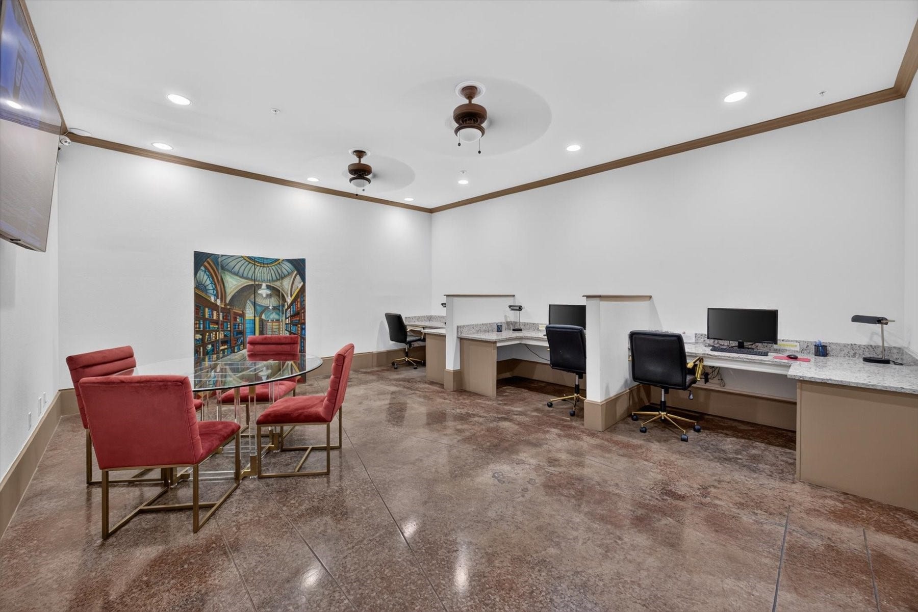 Residents have access to the modern office space featuring sleek workstations, a stylish glass-top meeting table with vibrant red chairs, and polished concrete floors, perfect for productivity.