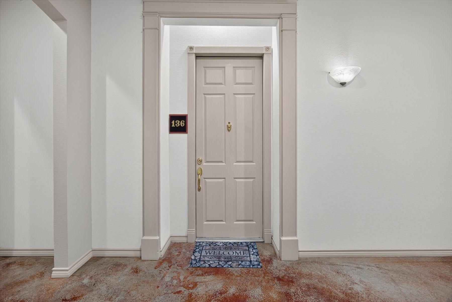 ONLY the first-floor condos offer 12-foot ceilings with concrete floors.  They have an elegant entryway with a classic door and warm lighting, offering a welcoming ambiance.