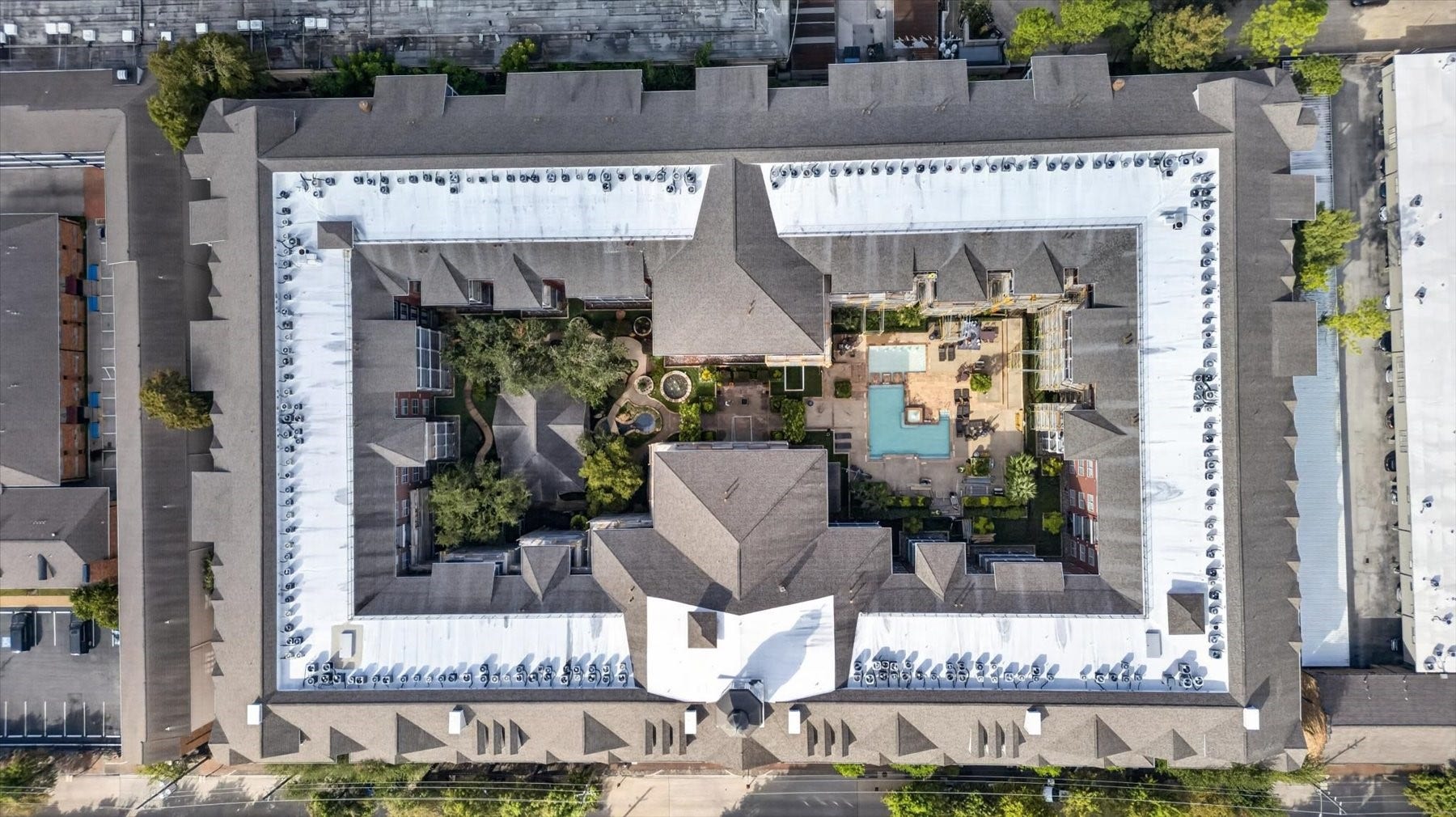 Aerial view of 2400 Mccue Condos featuring a central courtyard with lush greenery and a sparkling pool, offering a serene and private urban oasis.