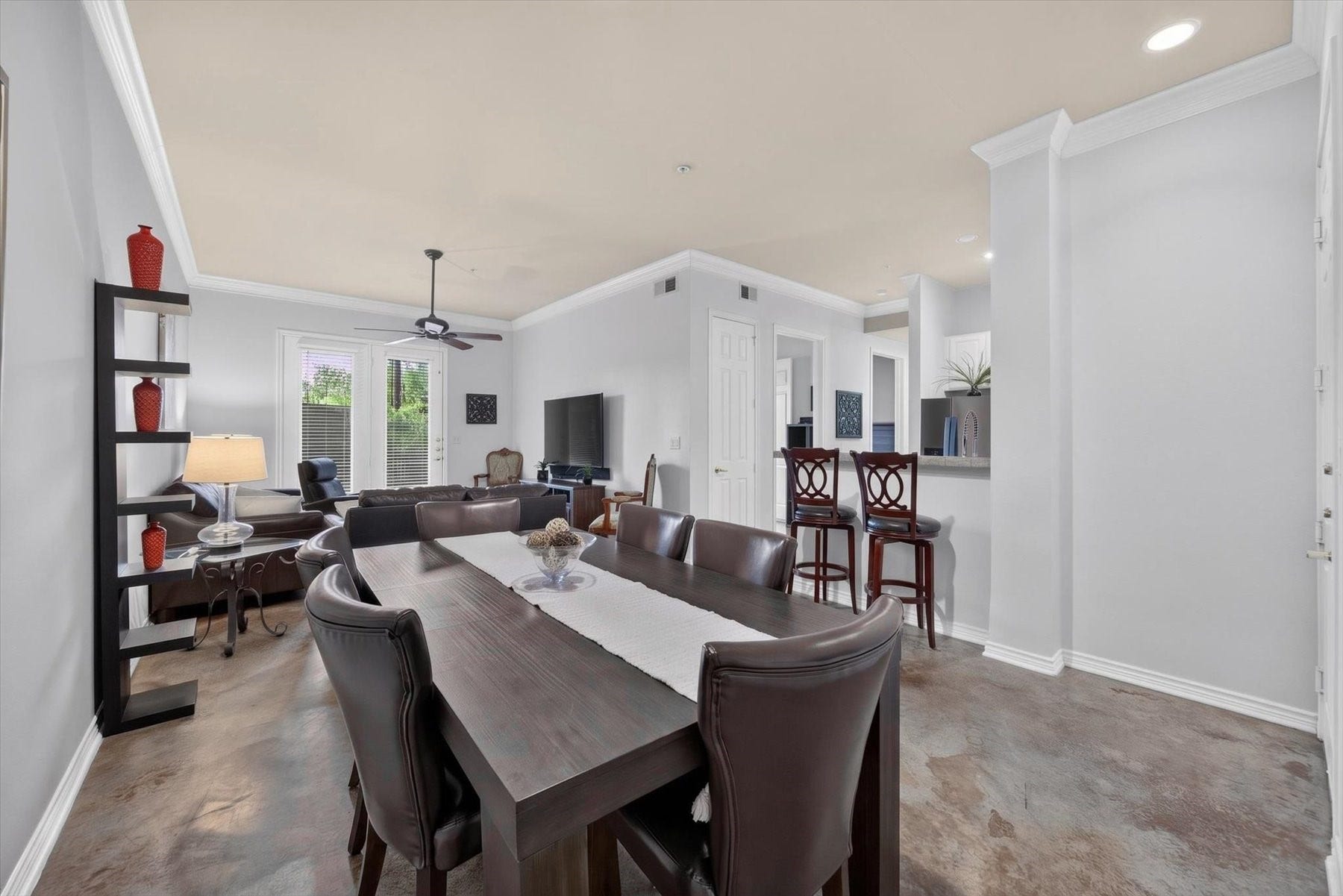 Spacious open-concept living area featuring elegant dining space, cozy seating, and a breakfast bar, all enhanced by natural light from large windows.