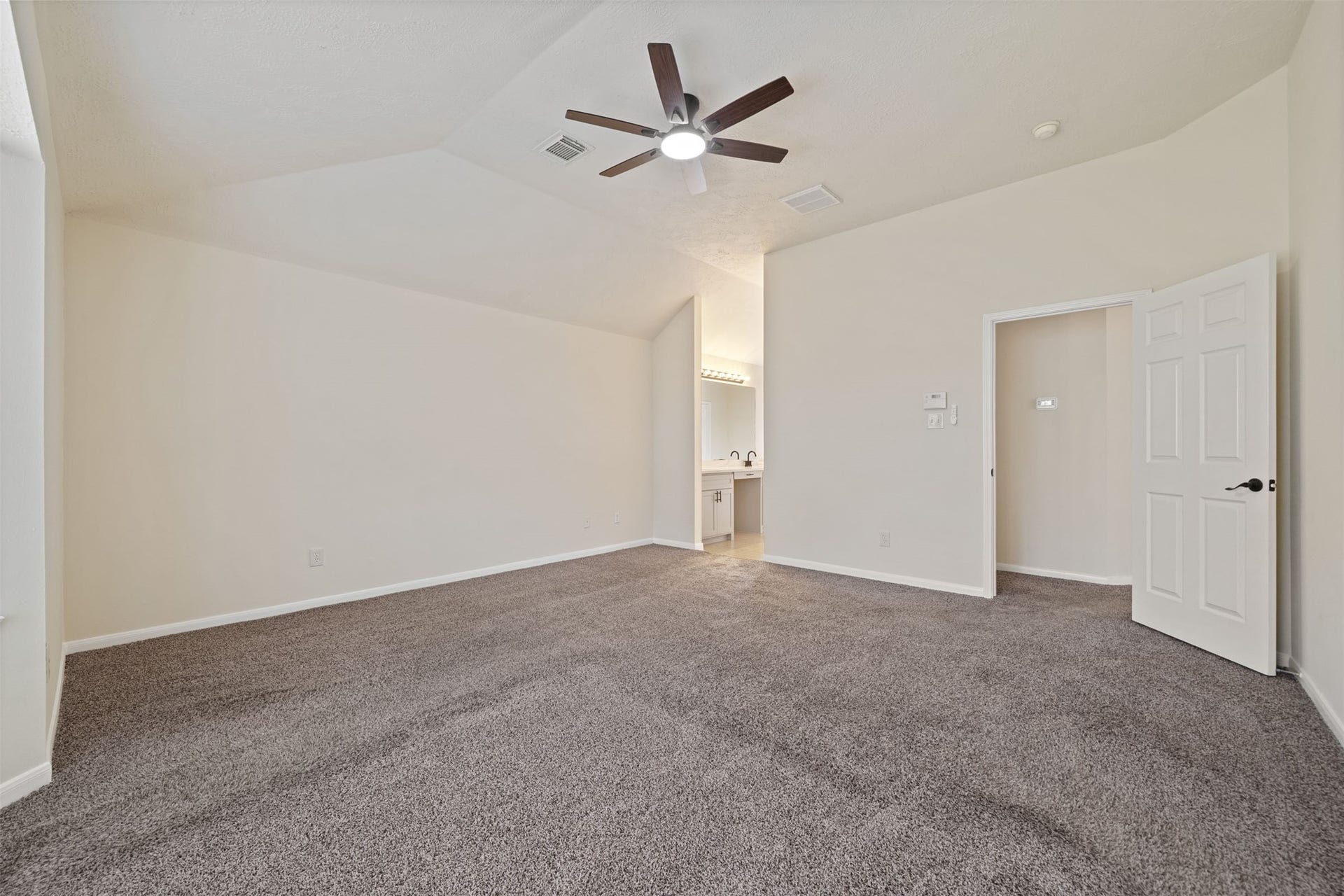 10902 Trail Ridge Drive, Houston, TX 77064 Plush carpeting, neutral walls, and a ceiling fan, featuring an open entrance to a well-lit en-suite bathroom for added convenience.