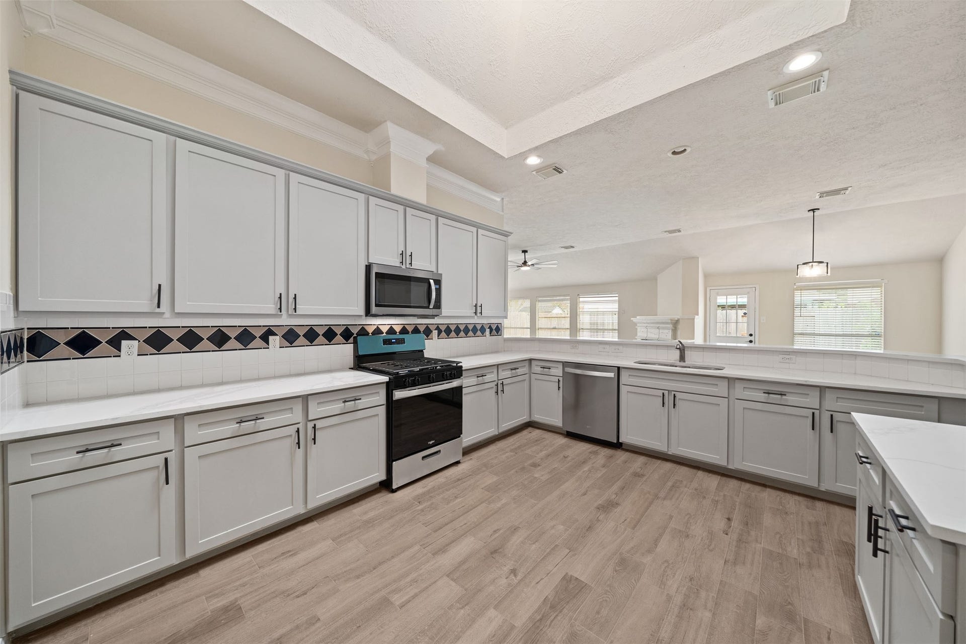 10902 Trail Ridge Drive, Houston, TX 77064 Oversized kitchen featuring an elegant tile backsplash, wood-style flooring, and a skylight
