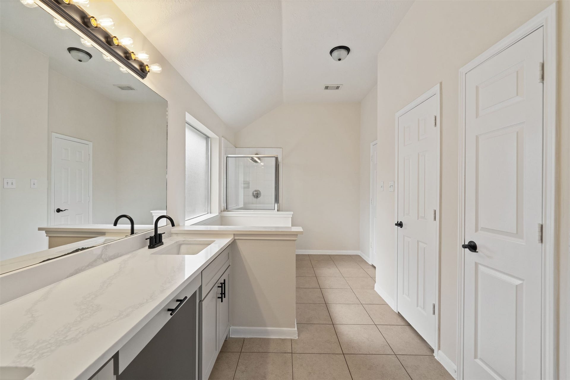 10902 Trail Ridge Drive, Houston, TX 77064 Renovated bathroom featuring a dual-sink vanity with modern fixtures, ample mirror space, and a large shower, all complemented by elegant tile flooring.