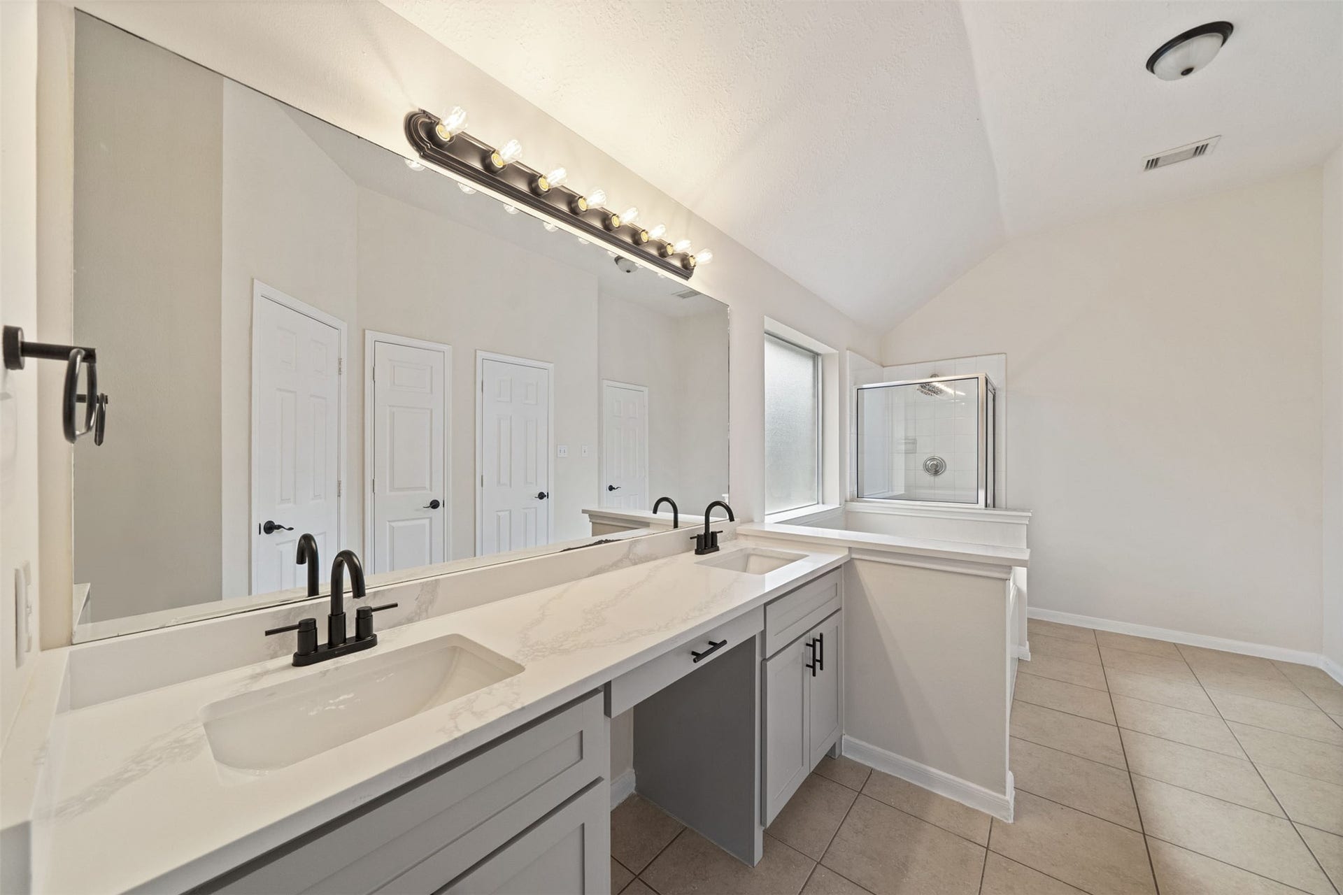 10902 Trail Ridge Drive, Houston, TX 77064 Renovated primary bathroom with modern dual sinks, elegant fixtures, a large mirror, and a glass-enclosed shower, offering a sleek and functional design.