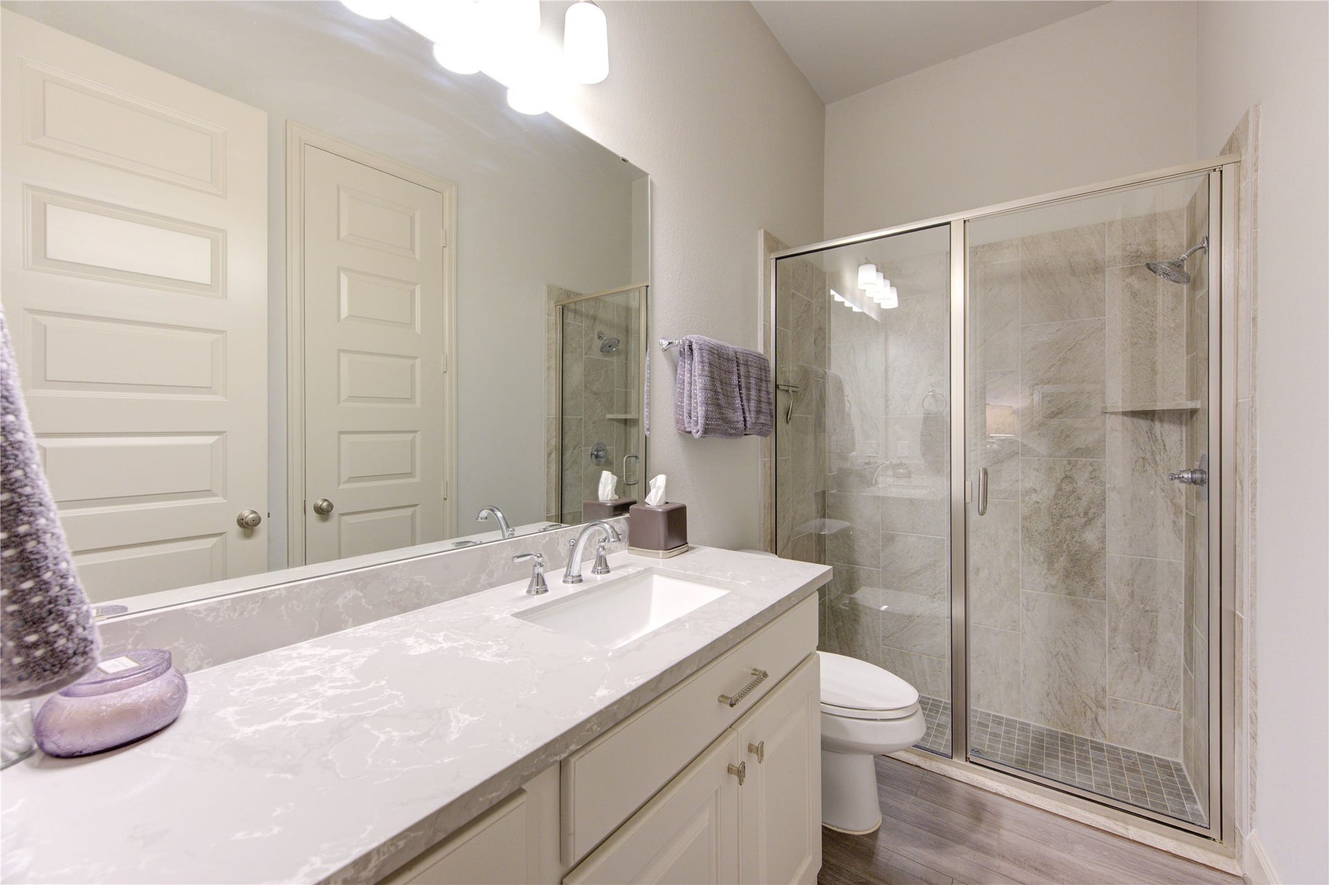 The secondary bathroom is designed with both style and functionality in mind, featuring sleek Quartz countertops that offer durability and a polished, modern look. The single vanity provides ample counter space and storage, while designer brushed nickel fixtures add a touch of elegance.

A walk-in shower with a frameless glass enclosure and contemporary tile surround enhances the bathrooms luxurious feel, offering a spa-like experience.