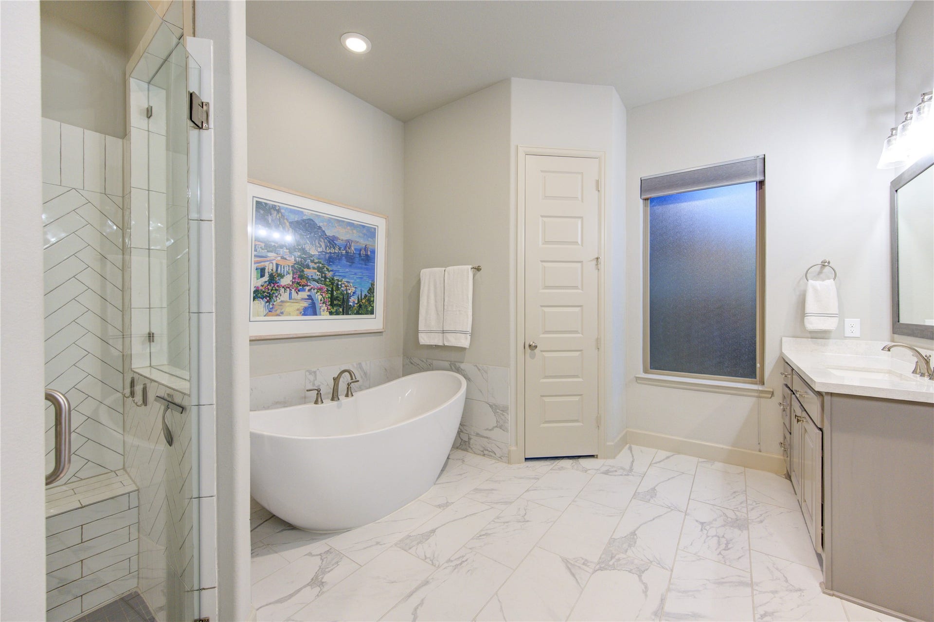 Adjacent to the tub, a walk-in shower with a frameless glass enclosure showcases modern tilework and a rainfall showerhead, creating a luxurious and rejuvenating experience.