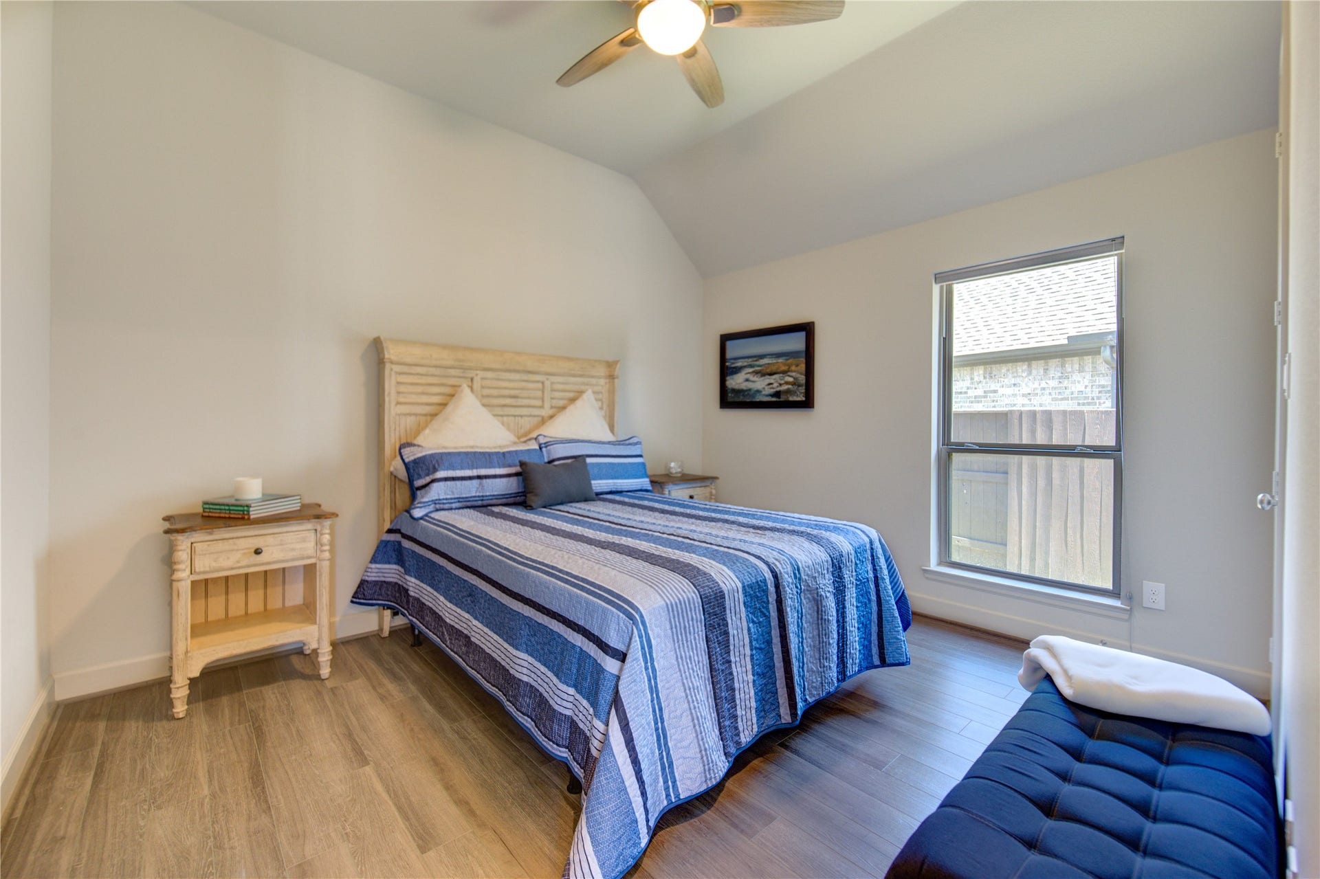 The third bedroom offers a spacious and comfortable retreat, featuring luxury vinyl floors, a ceiling fan, and ample natural light streaming in through large windows.