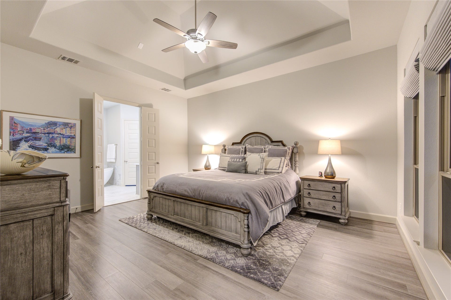 Tranquil Retreat with Lake Views: The spacious primary bedroom features a tray ceiling, plush carpeting, and large windows that frame the breathtaking lake view, offering a peaceful escape. His and her walk-n closets and one is oversized!