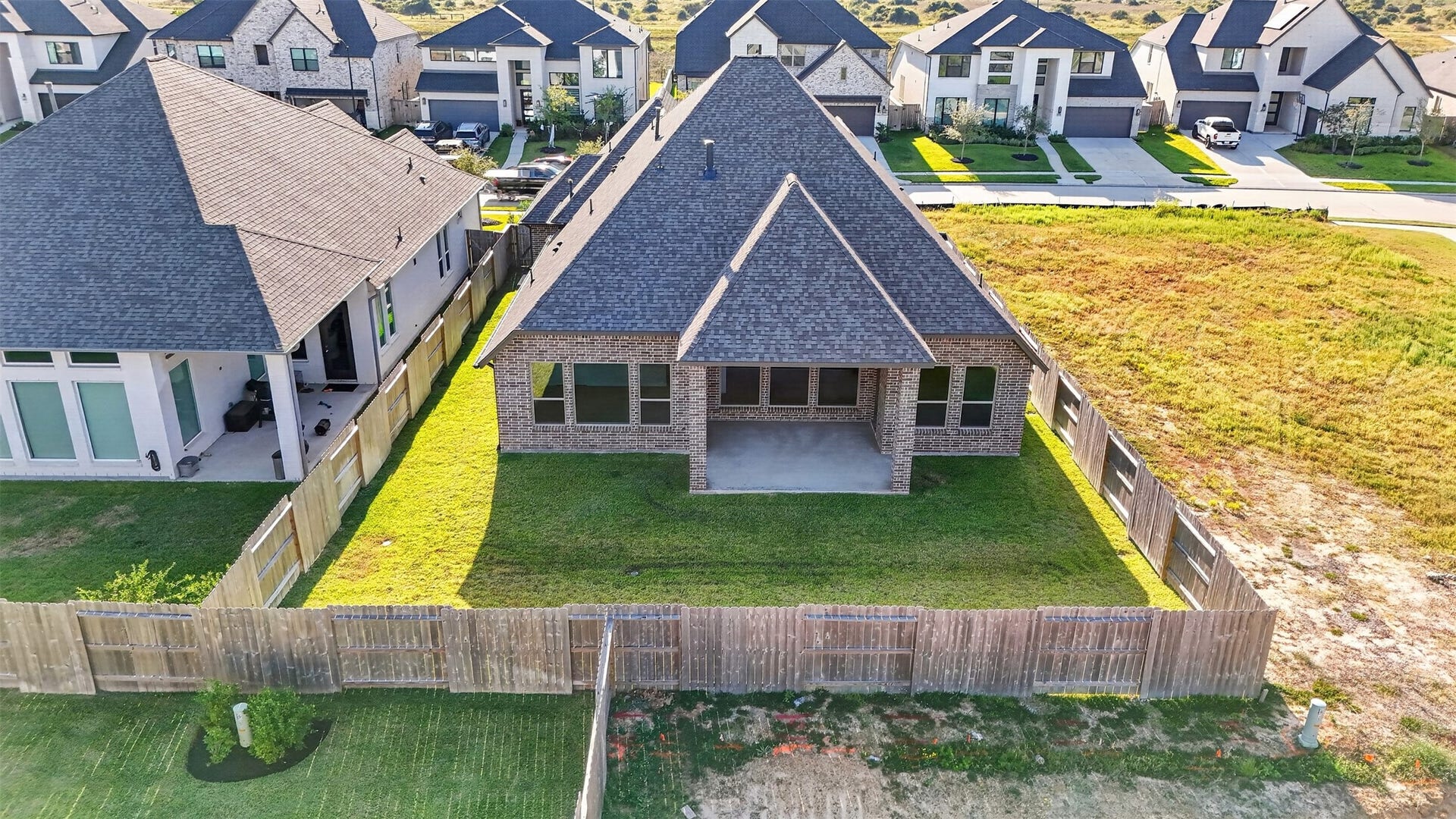 16270 Blue Mistflower Lane, Hockley, TX 77447 Aerial Rear Exterior & Backyard: Stunning aerial perspective showcasing the home's beautiful brick exterior, expansive covered patio, and spacious, fully fenced backyardoffering an inviting setting for outdoor living and entertaining.