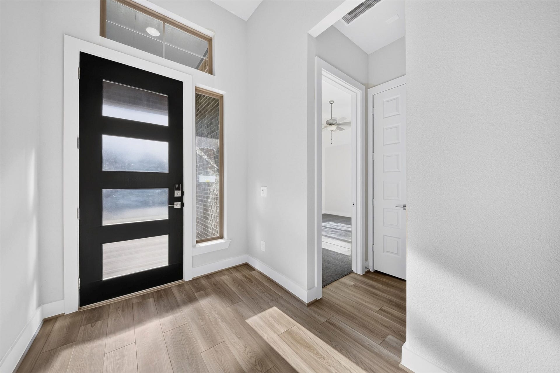 16270 Blue Mistflower Lane, Hockley, TX 77447 Front Entryway: Impressive entryway featuring soaring ceilings, a contemporary front door with glass accents, beautiful wood-look flooring, and abundant natural light that creates an inviting first impression.