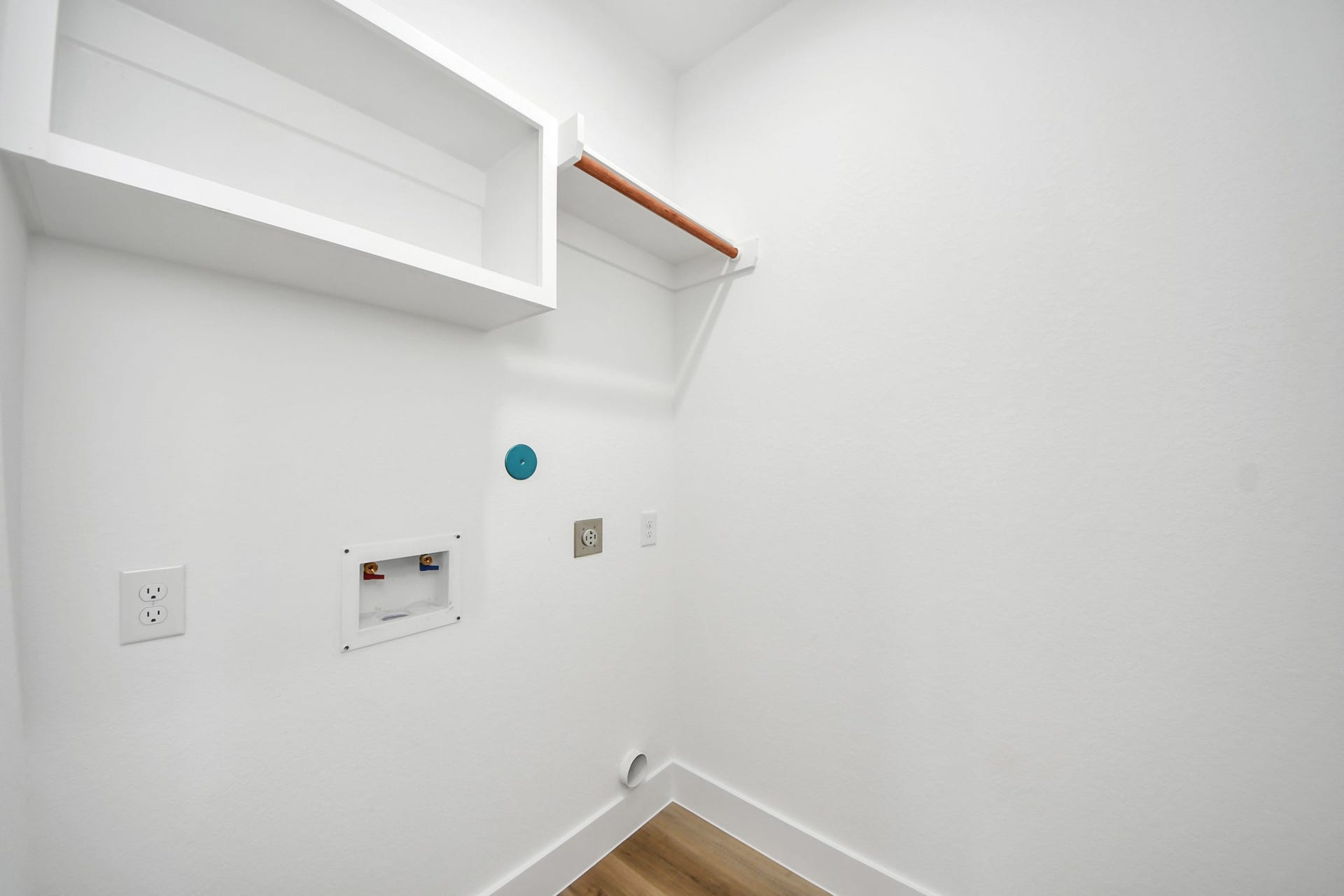7801 King Street, Houston, TX 77028 Laundry area equipped with hookups, a shelf for storage, and a hanging rod, offering convenience and functionality.