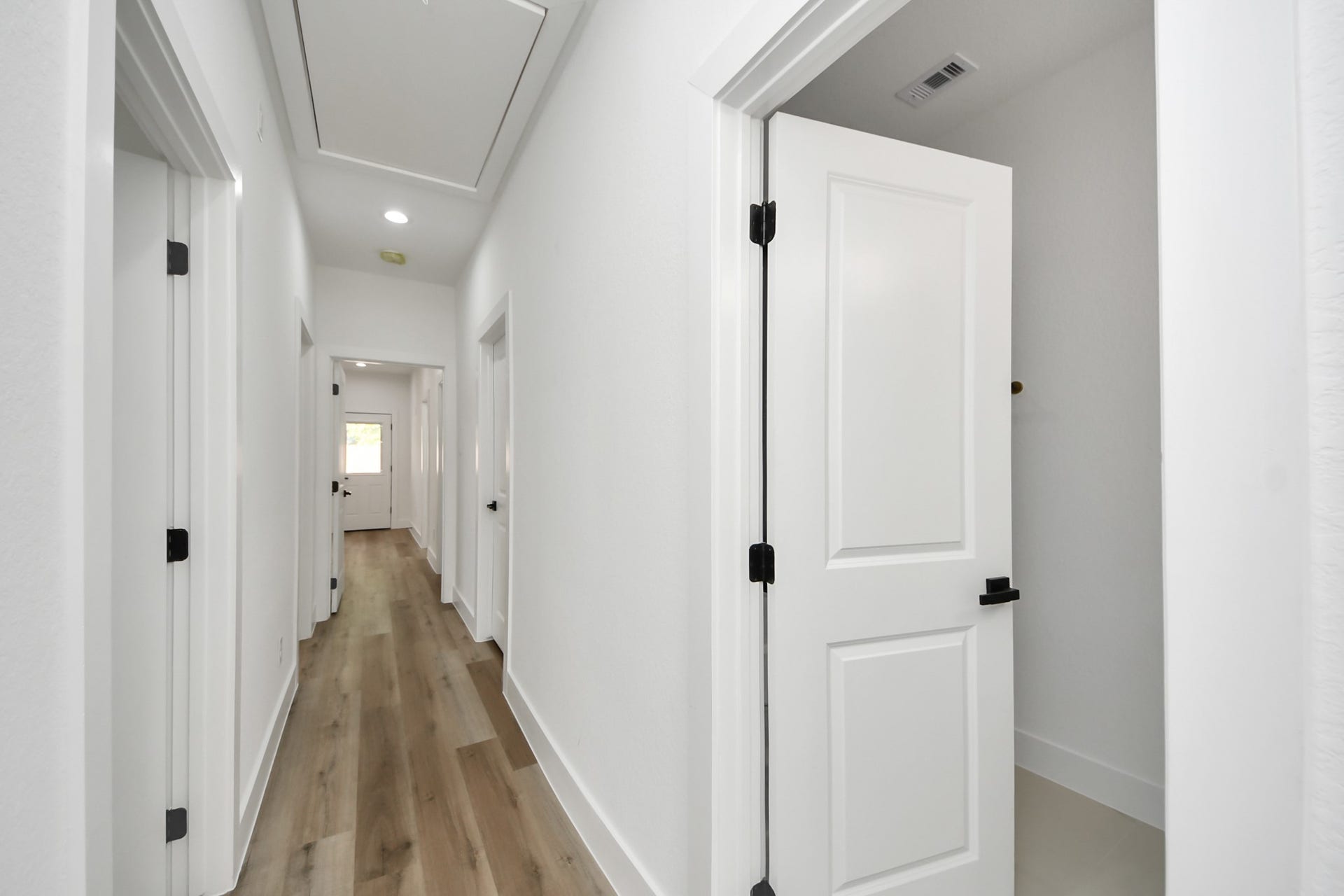 7801 King Street, Houston, TX 77028 Bright and inviting hallway with sleek wood flooring and modern white doors, leading to various rooms in the home.