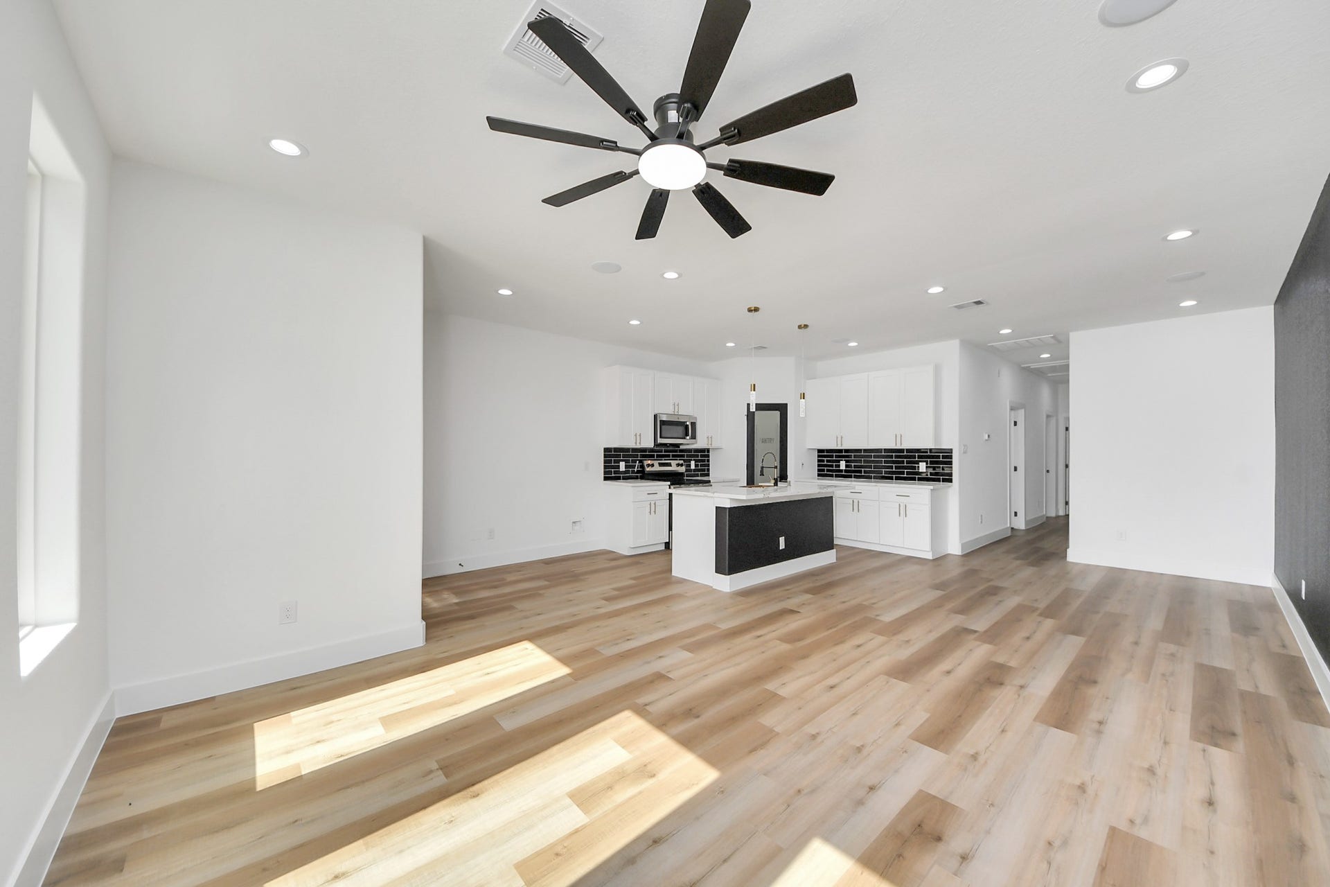 7801 King Street, Houston, TX 77028 Spacious open-concept living area featuring sleek hardwood floors, a modern kitchen with stylish black backsplash, and ample natural light.