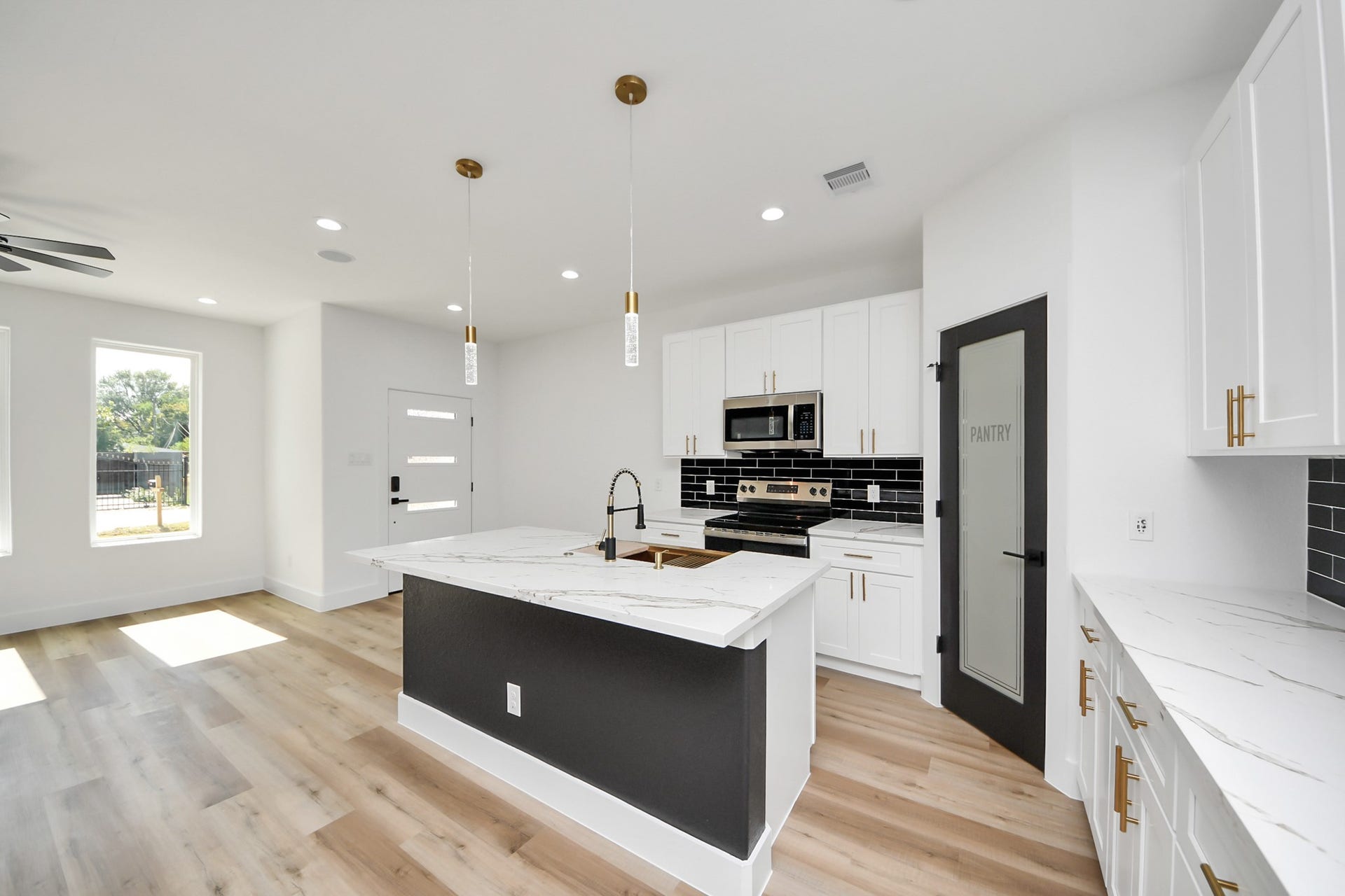 7801 King Street, Houston, TX 77028 Modern kitchen with sleek black and white cabinetry, marble countertops, and stainless steel appliances. Bright, open layout with stylish pendant lighting and a walk-in pantry.