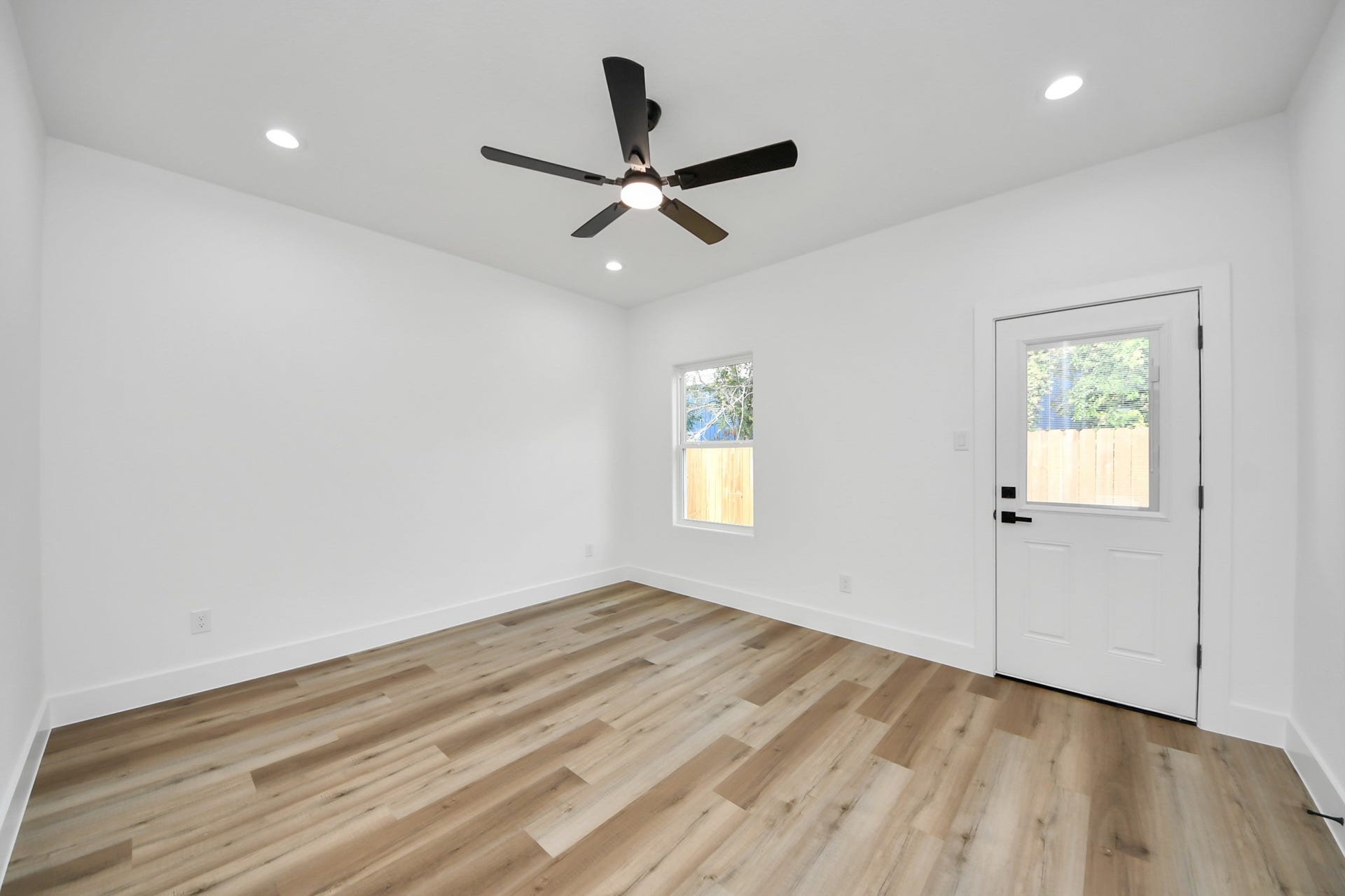 7801 King Street, Houston, TX 77028 Bright and inviting room featuring sleek hardwood floors, recessed lighting, and a modern ceiling fan, complemented by a window and door for ample natural light.