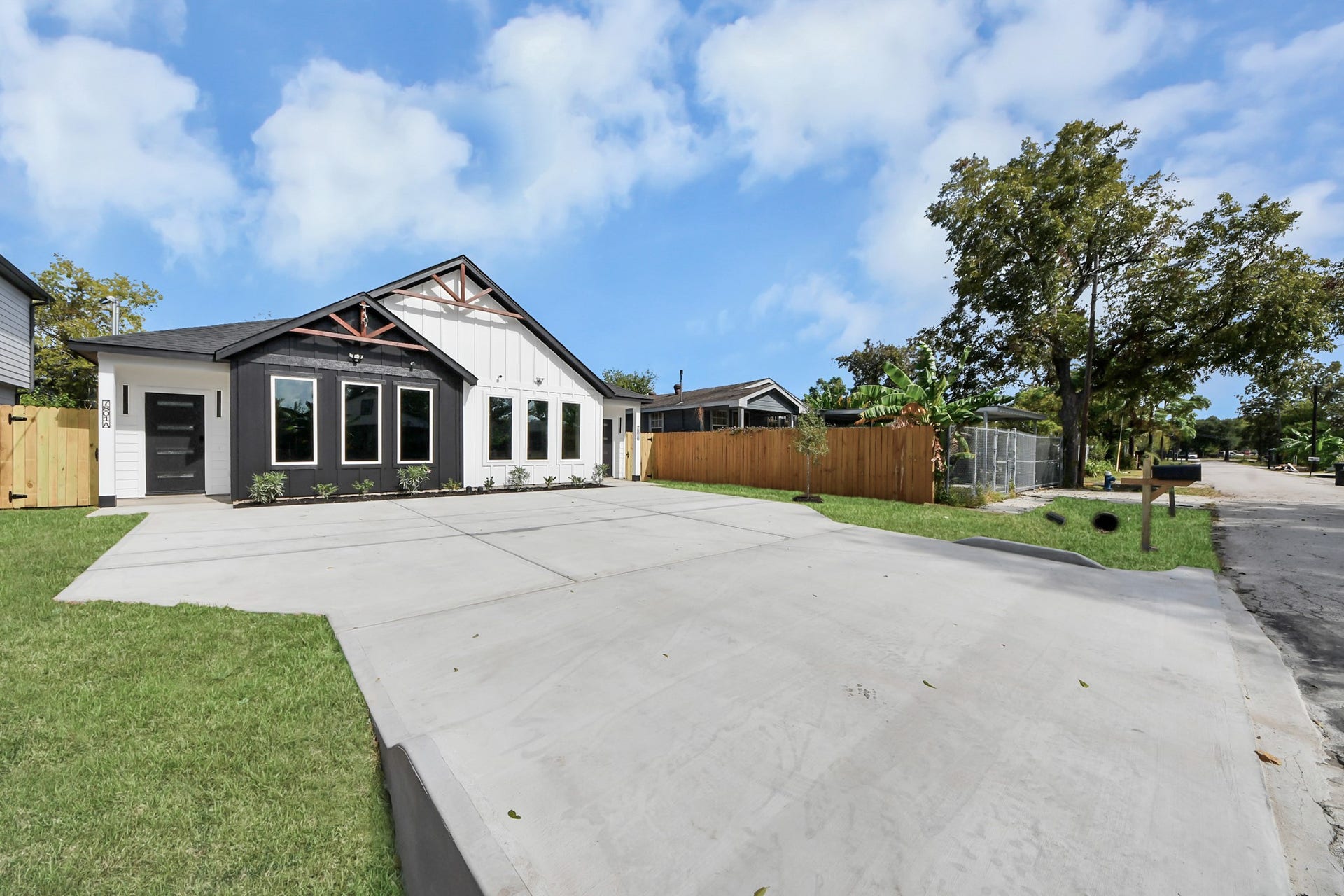 7801 King Street, Houston, TX 77028 Charming modern home with a striking black and white exterior, expansive windows, and a spacious driveway, nestled in a tranquil neighborhood.