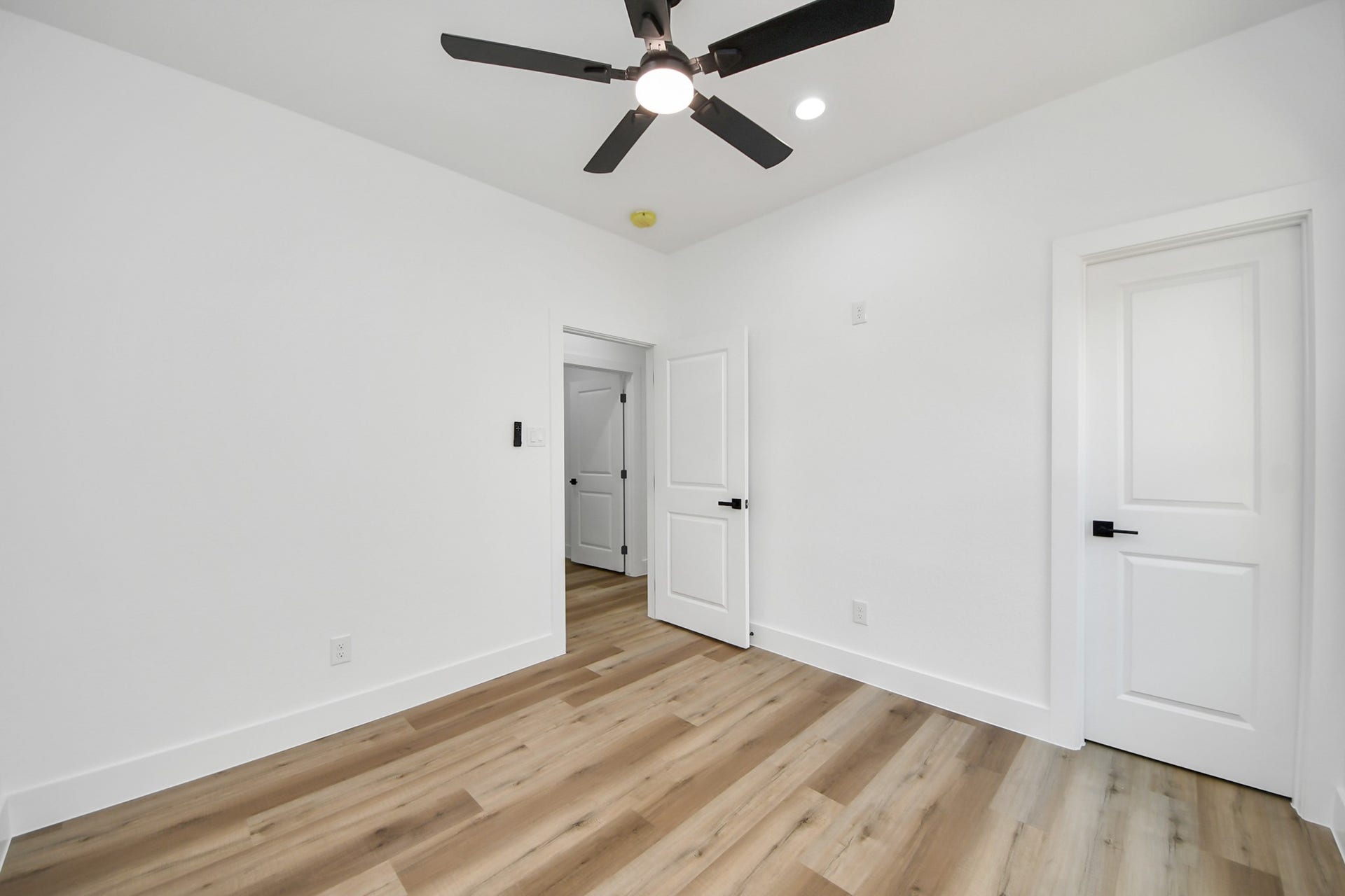 7801 King Street, Houston, TX 77028 Bright and airy bedroom featuring sleek wood flooring, modern ceiling fan, and crisp white walls for a fresh, inviting atmosphere.