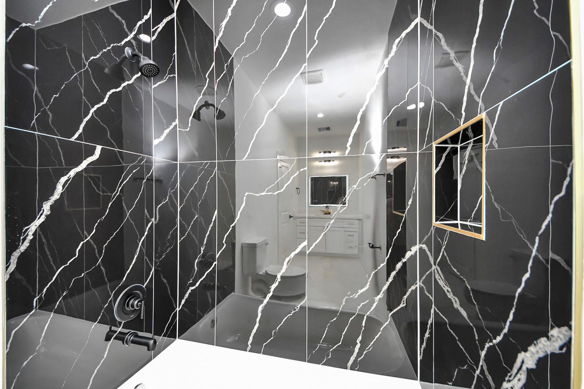 7801 King Street, Houston, TX 77028 Luxurious bathroom featuring elegant black marble tiles with striking white veining, complemented by modern fixtures for a sophisticated look.