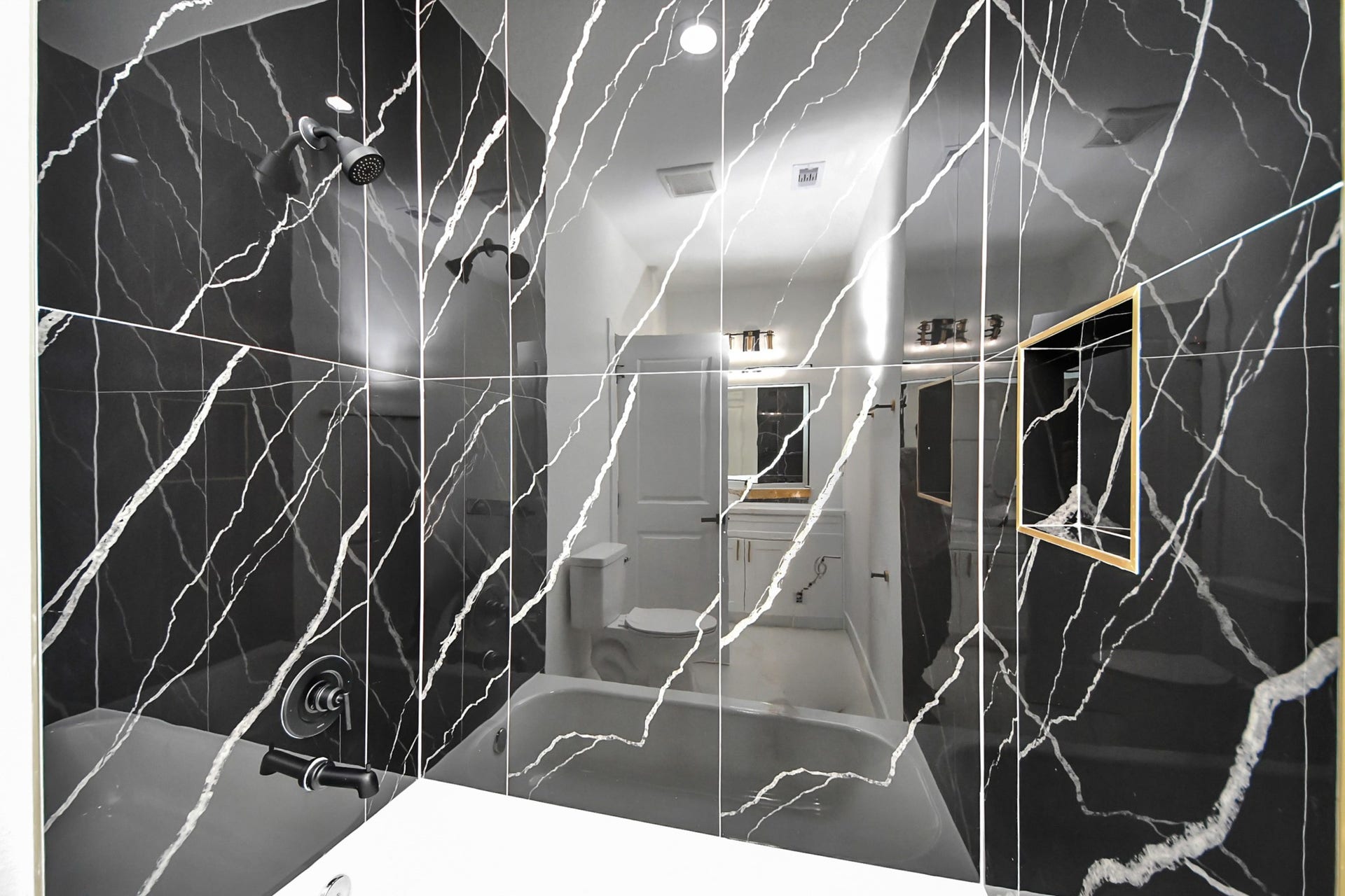 7801 King Street, Houston, TX 77028 Elegant bathroom featuring striking black marble tiles with white veining, a modern showerhead, and sleek fixtures, creating a luxurious and contemporary feel.