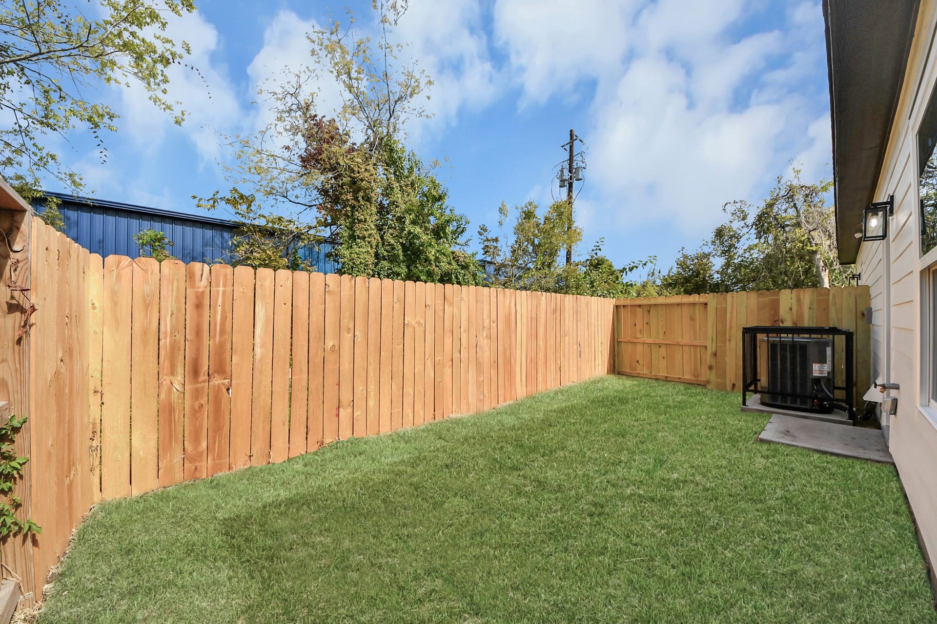 7801 King Street, Houston, TX 77028 A private backyard oasis featuring a lush green lawn and a wooden privacy fence, perfect for relaxation and outdoor activities.