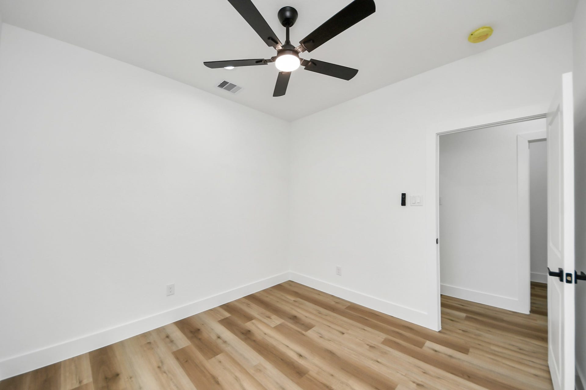7801 King Street, Houston, TX 77028 Bright and inviting room with sleek hardwood floors, a modern ceiling fan, and crisp white walls, perfect for a cozy bedroom or home office.