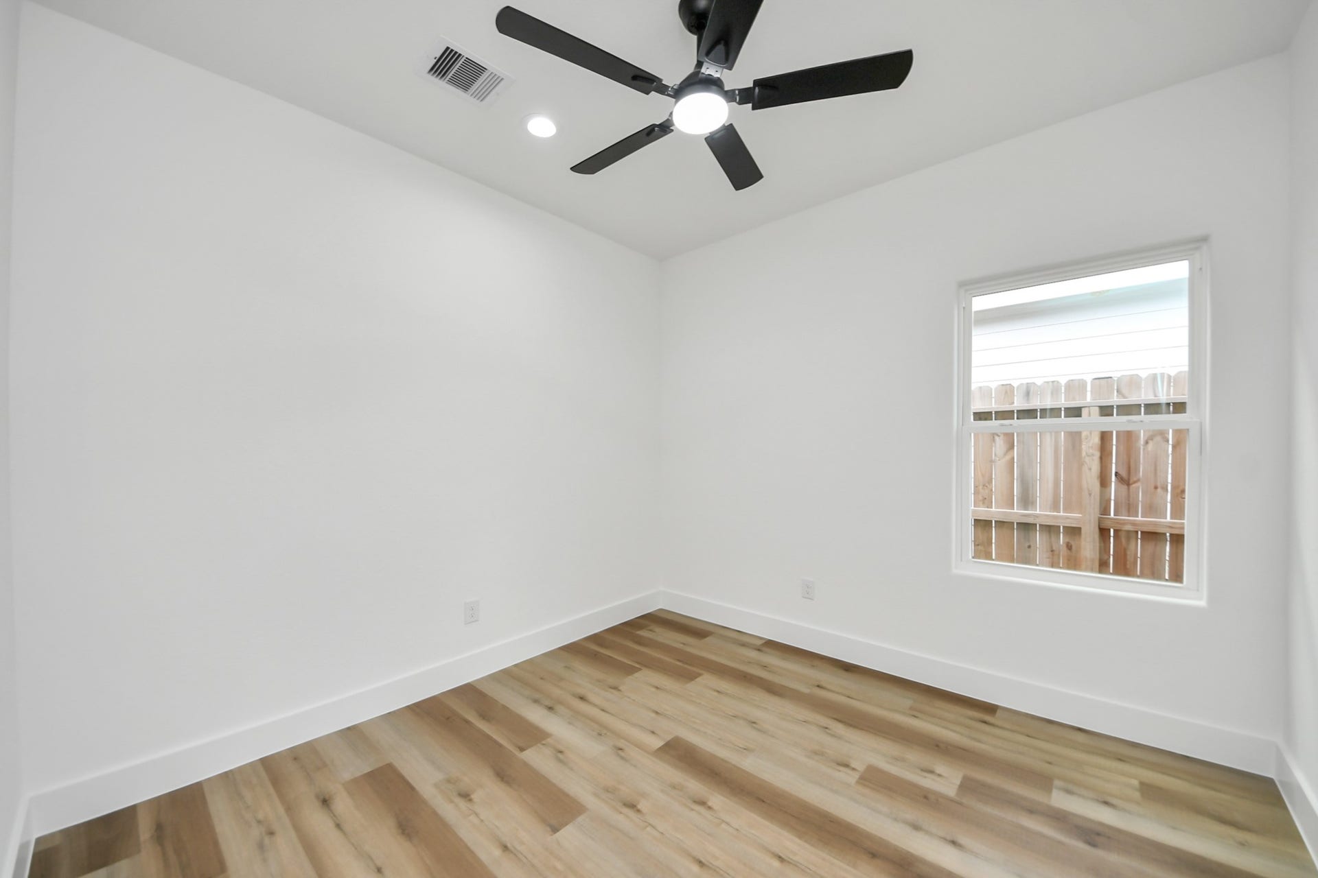7801 King Street, Houston, TX 77028 Bright room with sleek wood flooring, modern ceiling fan, and ample natural light from the window.