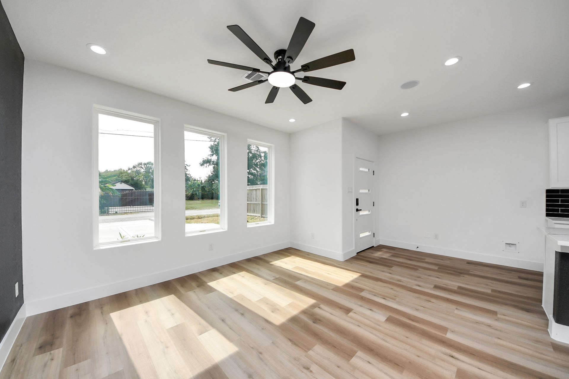 7801 King Street, Houston, TX 77028 Bright and airy living space featuring large windows, sleek ceiling fan, and elegant wood flooring, offering a welcoming and modern ambiance.