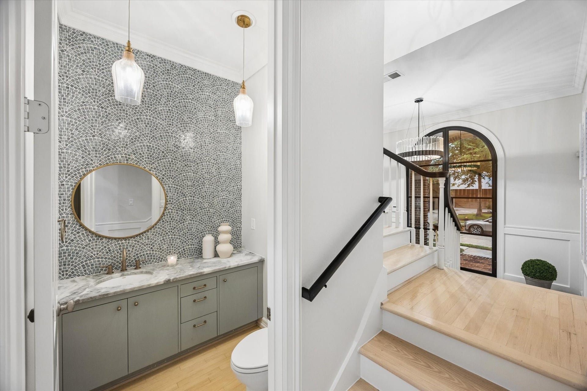 Stylish first-floor powder room makes a statement with a dramatic mosaic accent wall, floating vanity with stone countertop, designer lighting and sophisticated finishes.