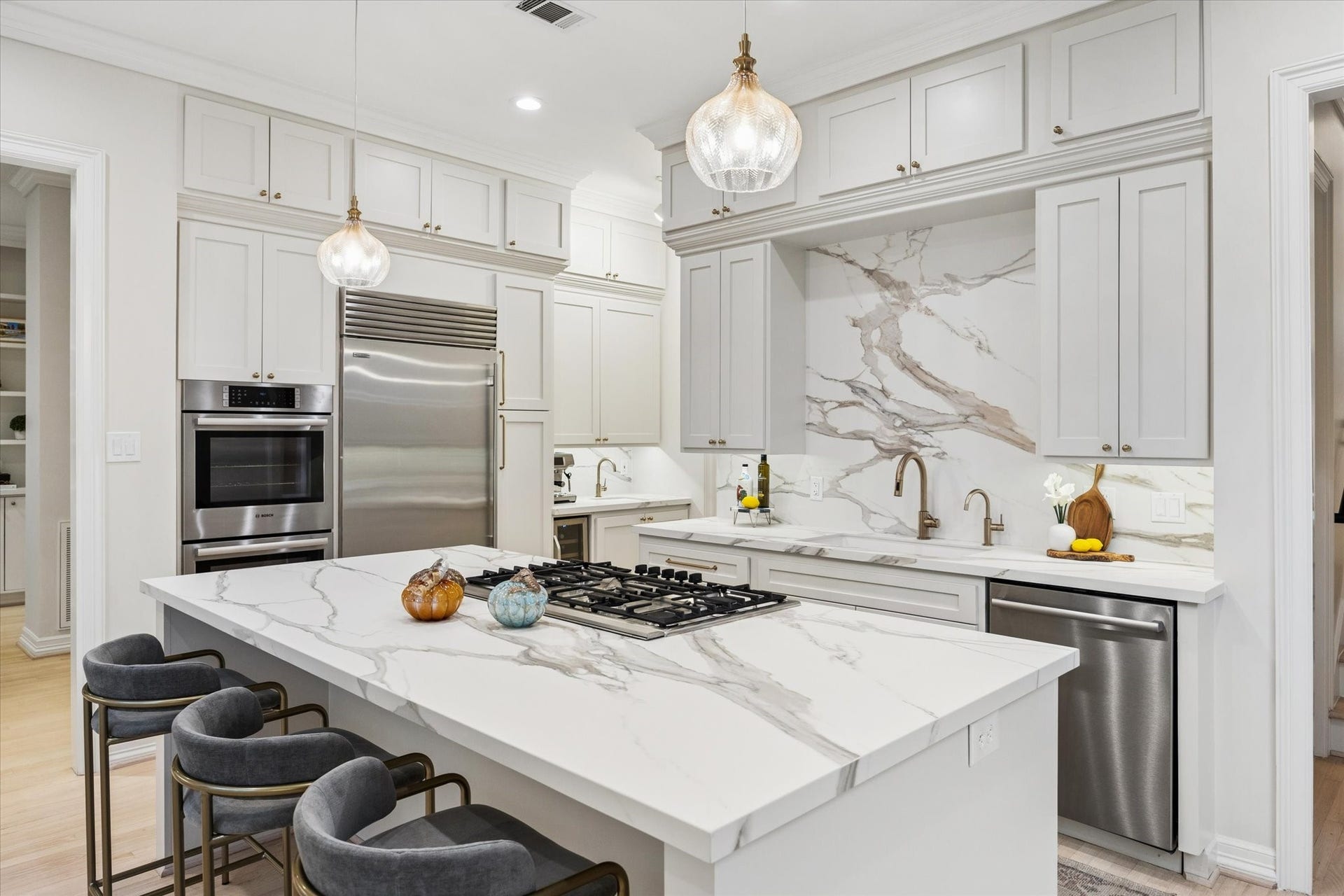 Designed for both everyday living and entertaining, the kitchen features a Sub-Zero refrigerator, gas cooktop, generous island seating and an elegant stone backsplash extending dramatically behind the cooking area.