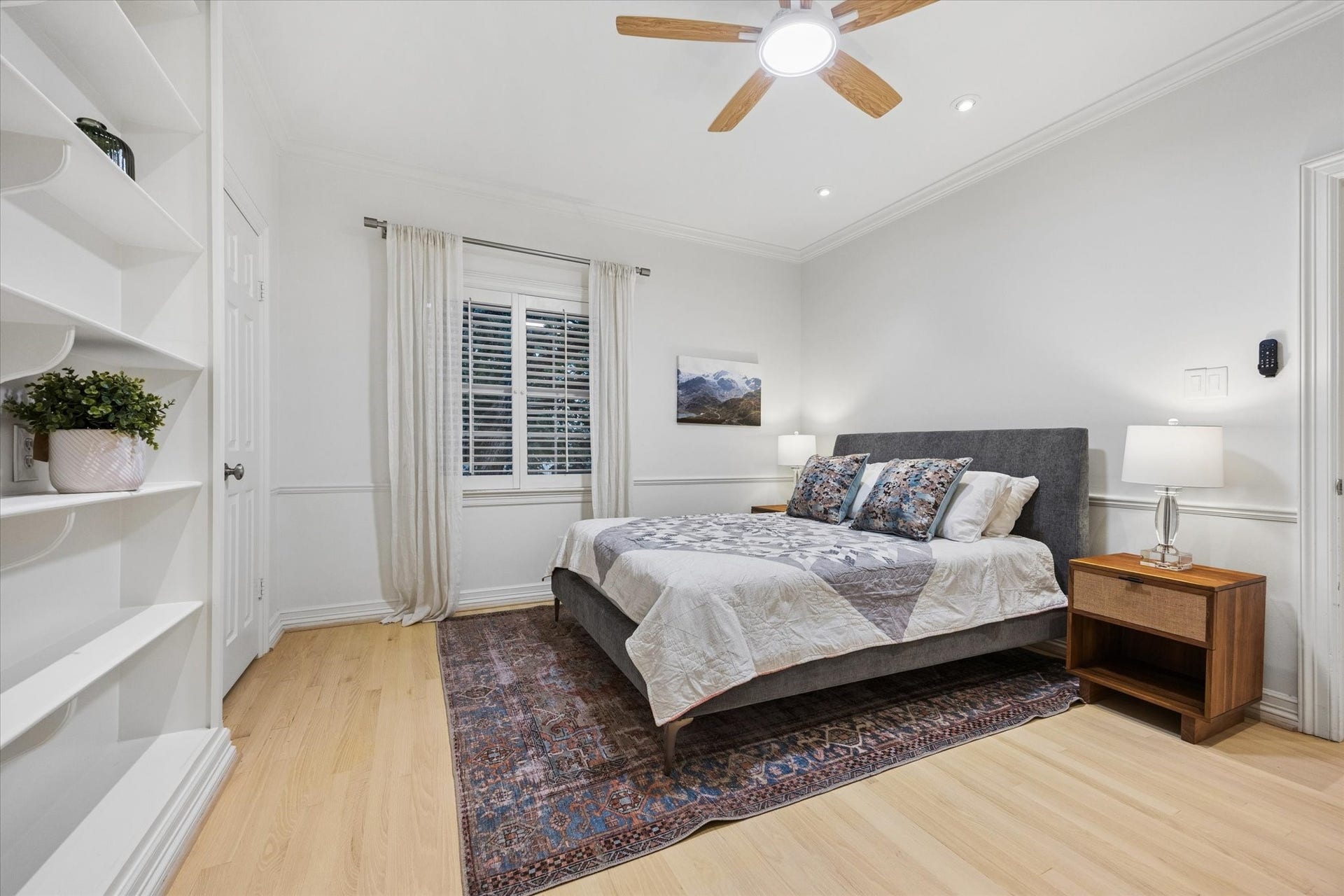 Another spacious secondary bedroom featuring extensive built-in shelving and abundant natural light.