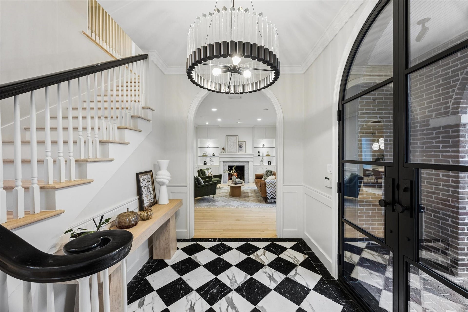 Another view of the elegant foyer highlights the graceful curved staircase, dramatic designer chandelier and beautiful sightline into the main living spaces.