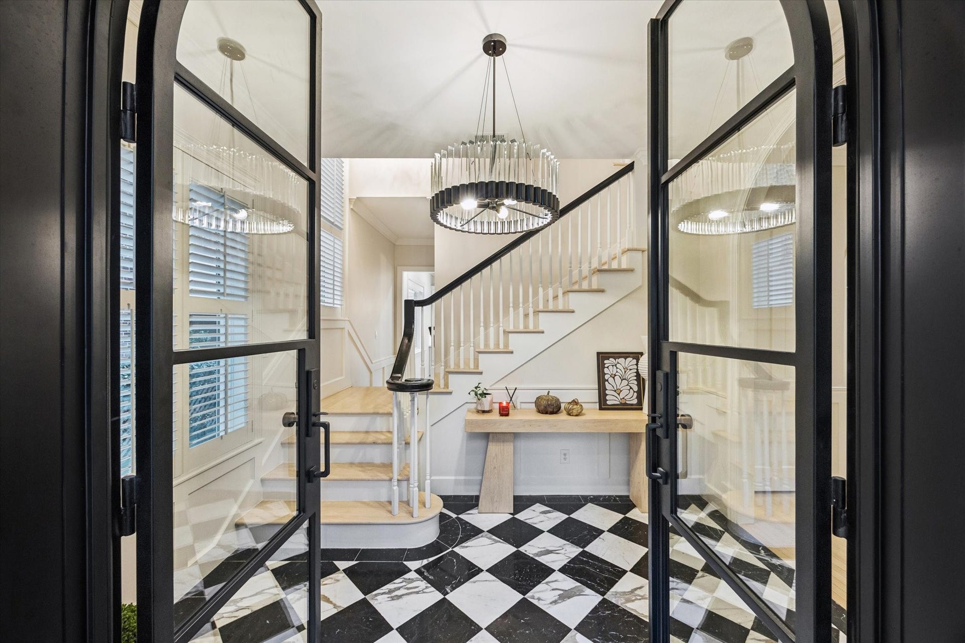 A dramatic entry foyer makes an unforgettable first impression with striking black-and-white marble floors, a graceful curved staircase, designer lighting and custom iron-and-glass doors.