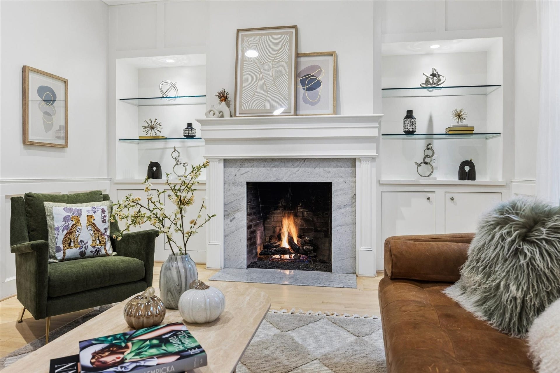 The classic fireplace serves as a beautiful focal point, flanked by custom illuminated built-ins that add both architectural character and sophisticated display space.