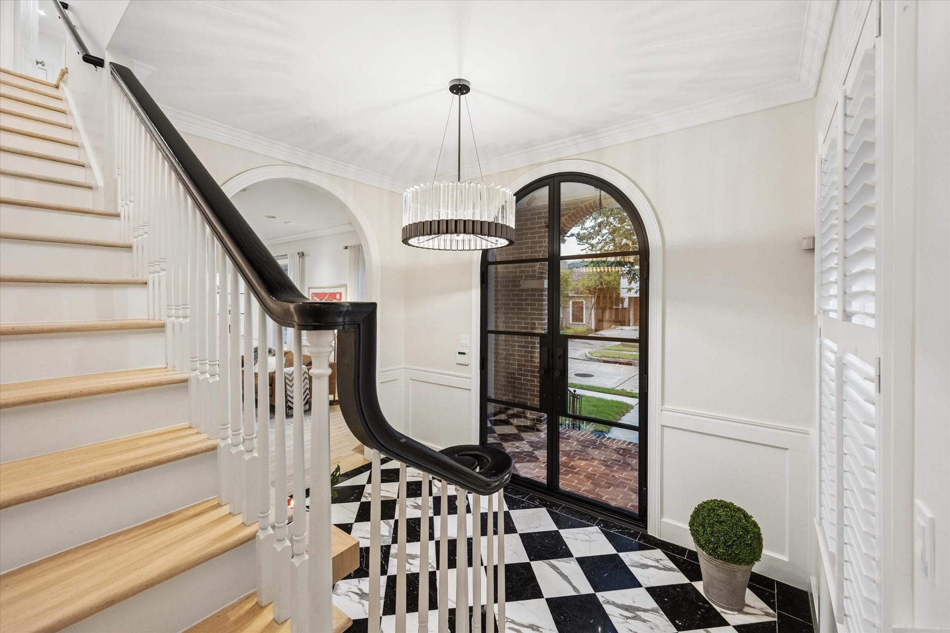 Elegant staircase leading to the second floor, beautifully framed by the dramatic arched entry and classic architectural details.