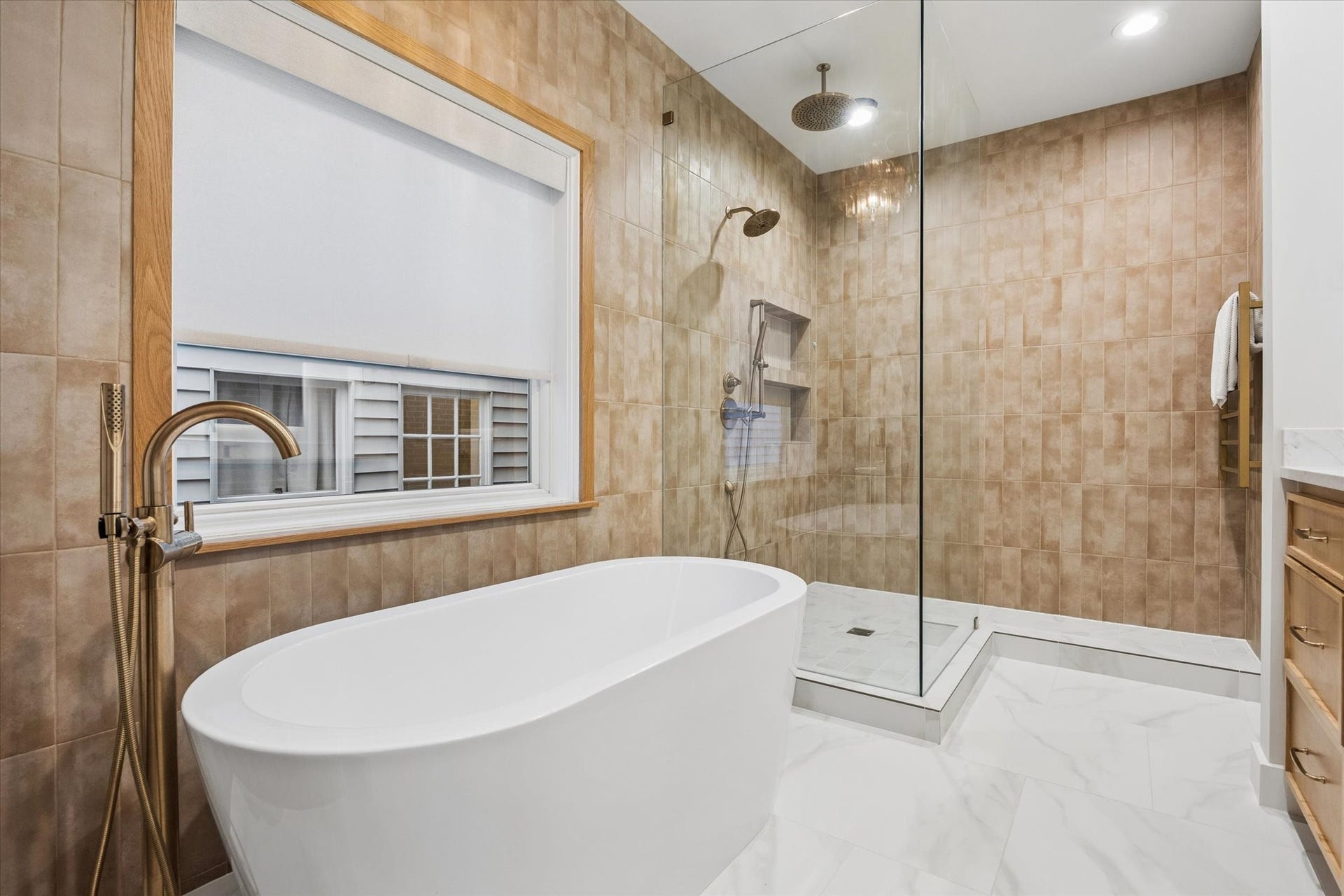 Spa-inspired primary bath featuring a freestanding soaking tub and oversized glass-enclosed walk-in shower with dual showerheads and beautiful floor-to-ceiling tile.