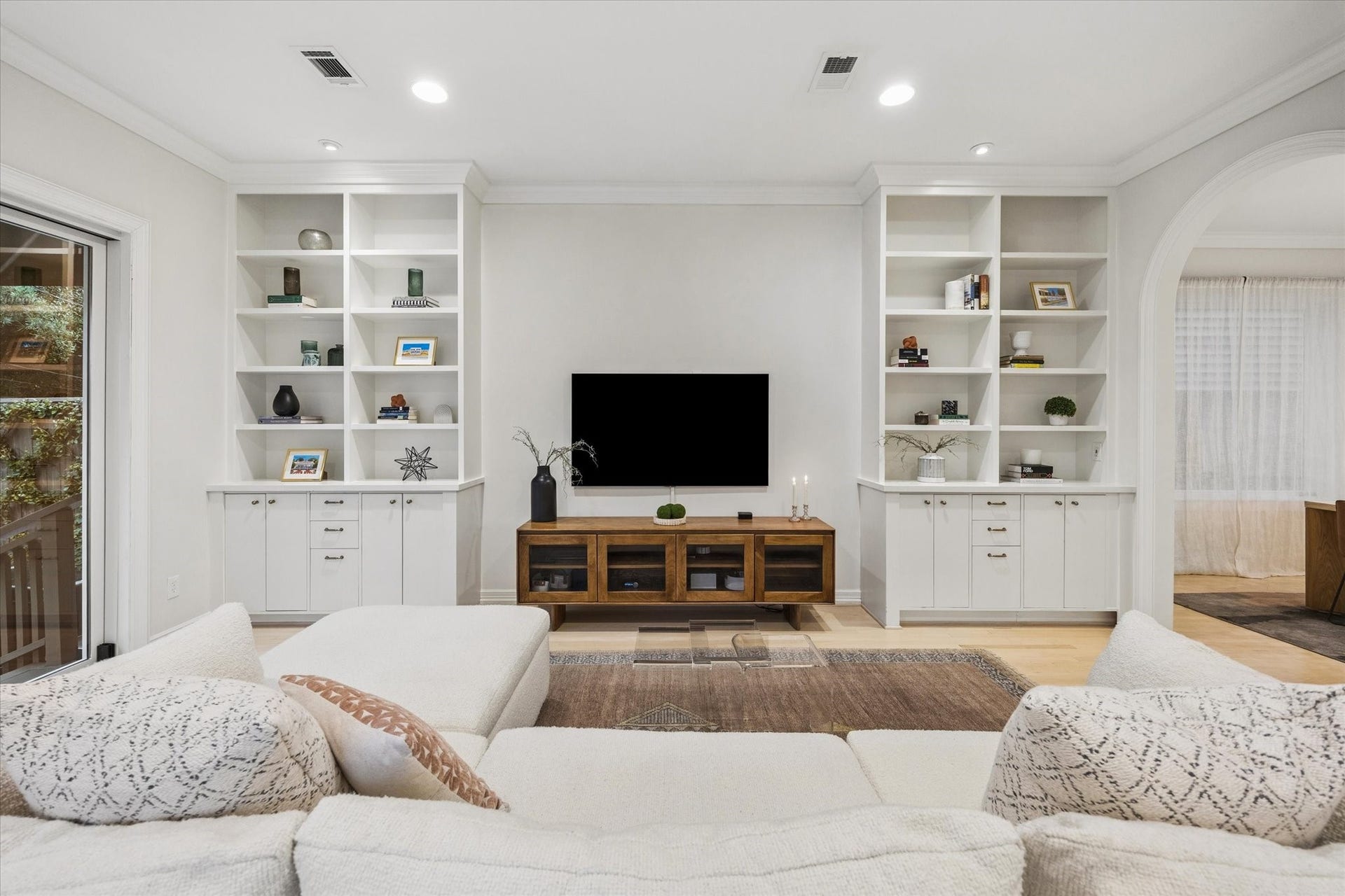 Spacious and inviting family room with built-in shelving and cabinetry, a seamless connection to the kitchen and dining areas, and double doors opening directly to the backyardperfect for relaxed indoor-outdoor living and entertaining.