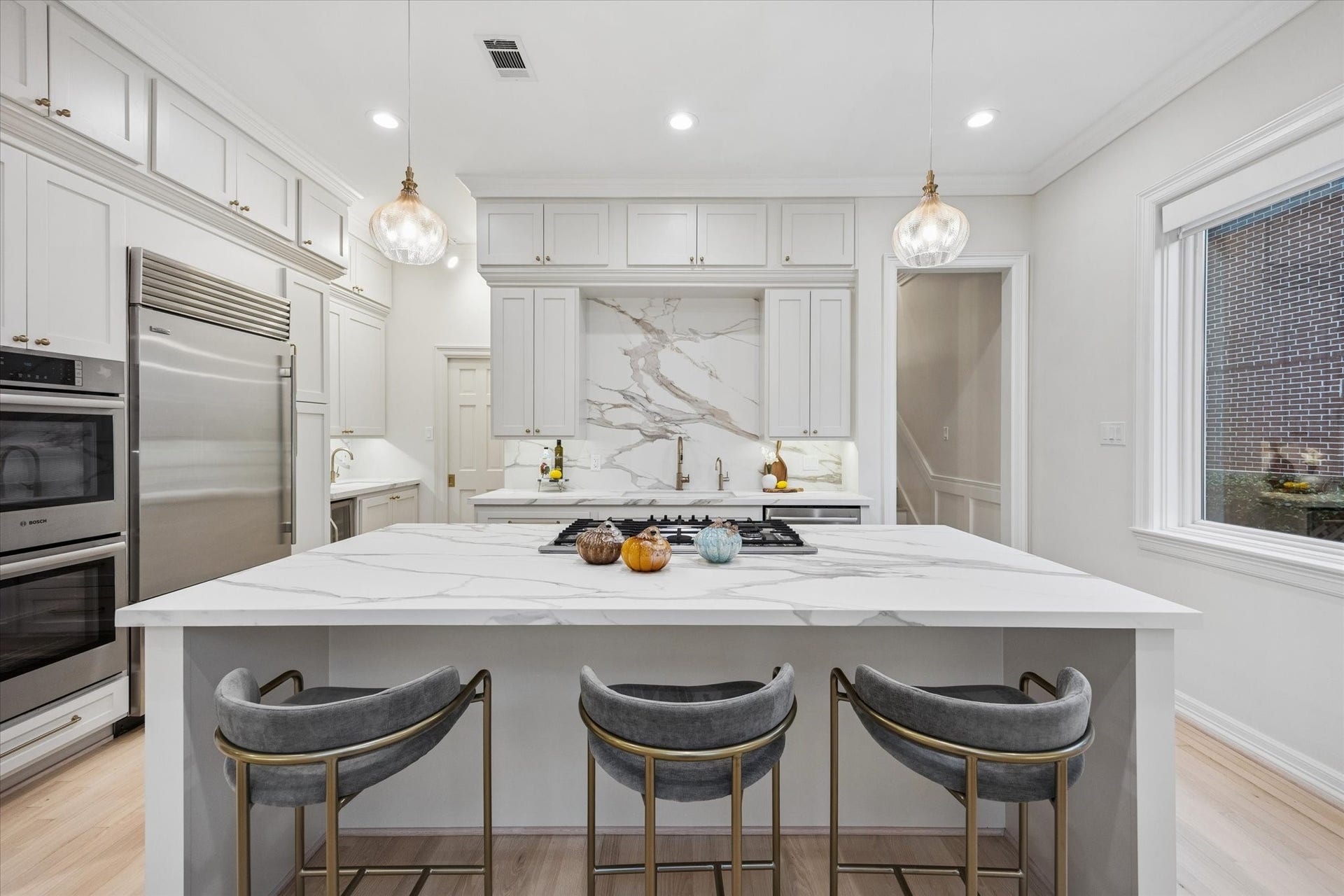 Stunning remodeled kitchen featuring an oversized waterfall-edge island, beautiful stone surfaces, premium stainless-steel appliances and designer lightingan exceptional centerpiece for cooking and entertaining.