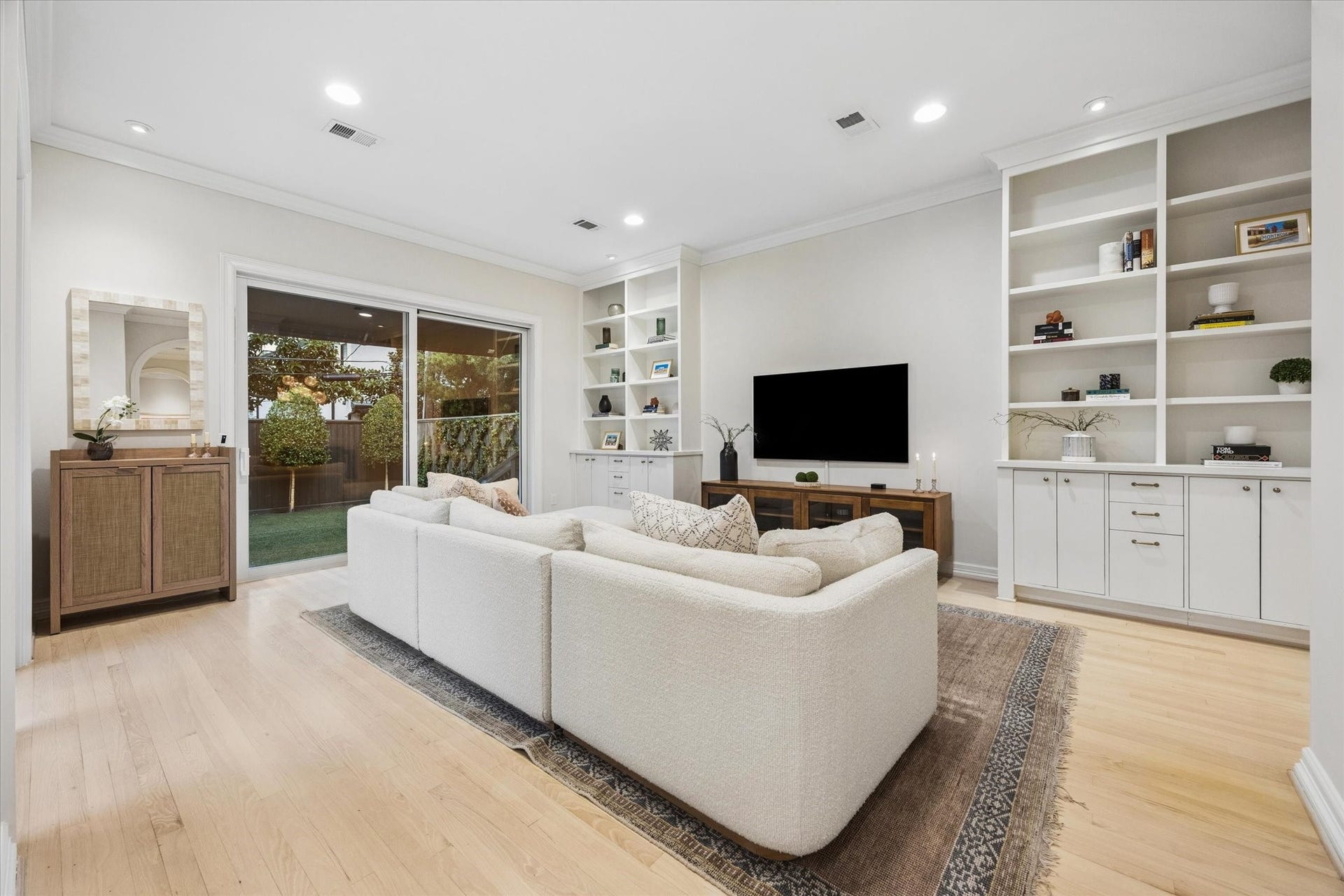 Another view of the spacious family room highlights the custom built-ins and double doors opening to the backyard, bringing beautiful natural light and an easy indoor-outdoor connection.