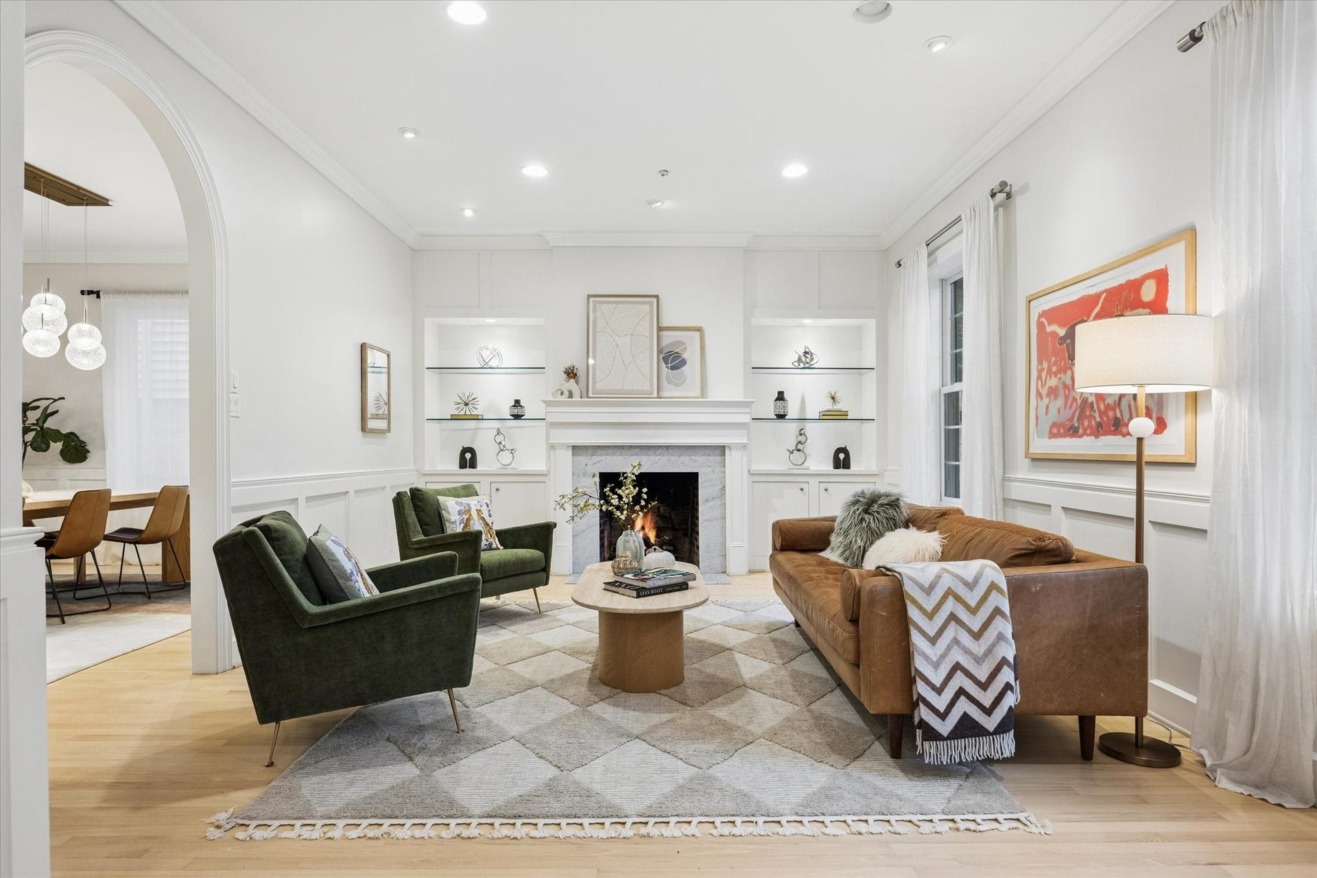 Elegant formal living room featuring a classic fireplace framed by custom built-ins, beautiful hardwood floors and abundant natural lightan inviting space for both everyday living and entertaining.