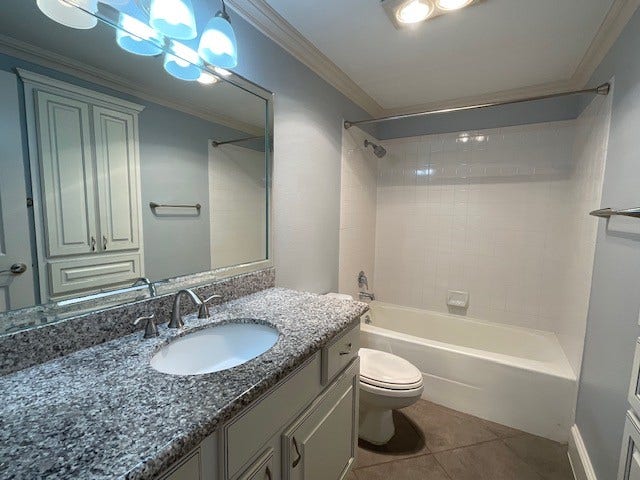 Secondary bathroom features stone countertop and large linin closet.