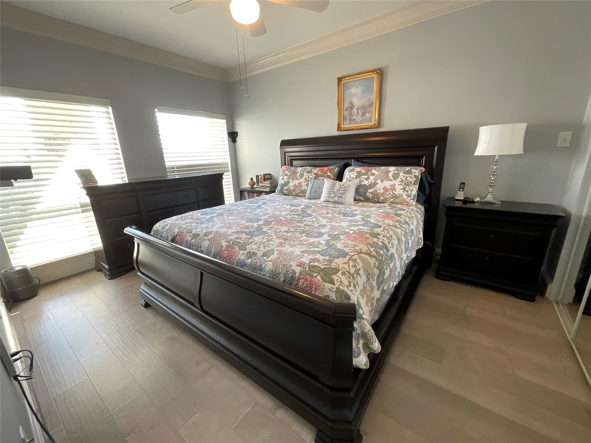 Spacious Primary bedroom, overlooking the lake, has wood flooring, triple crown molding, high baseboards and ceiling fans.  Large mirrored closet