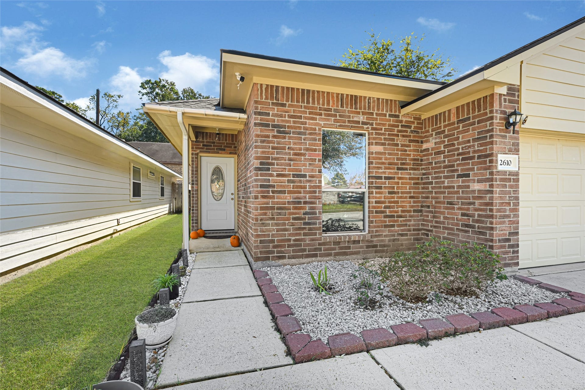 Charming brick exterior with a welcoming front entry, featuring a decorative door and a tidy landscaped path.