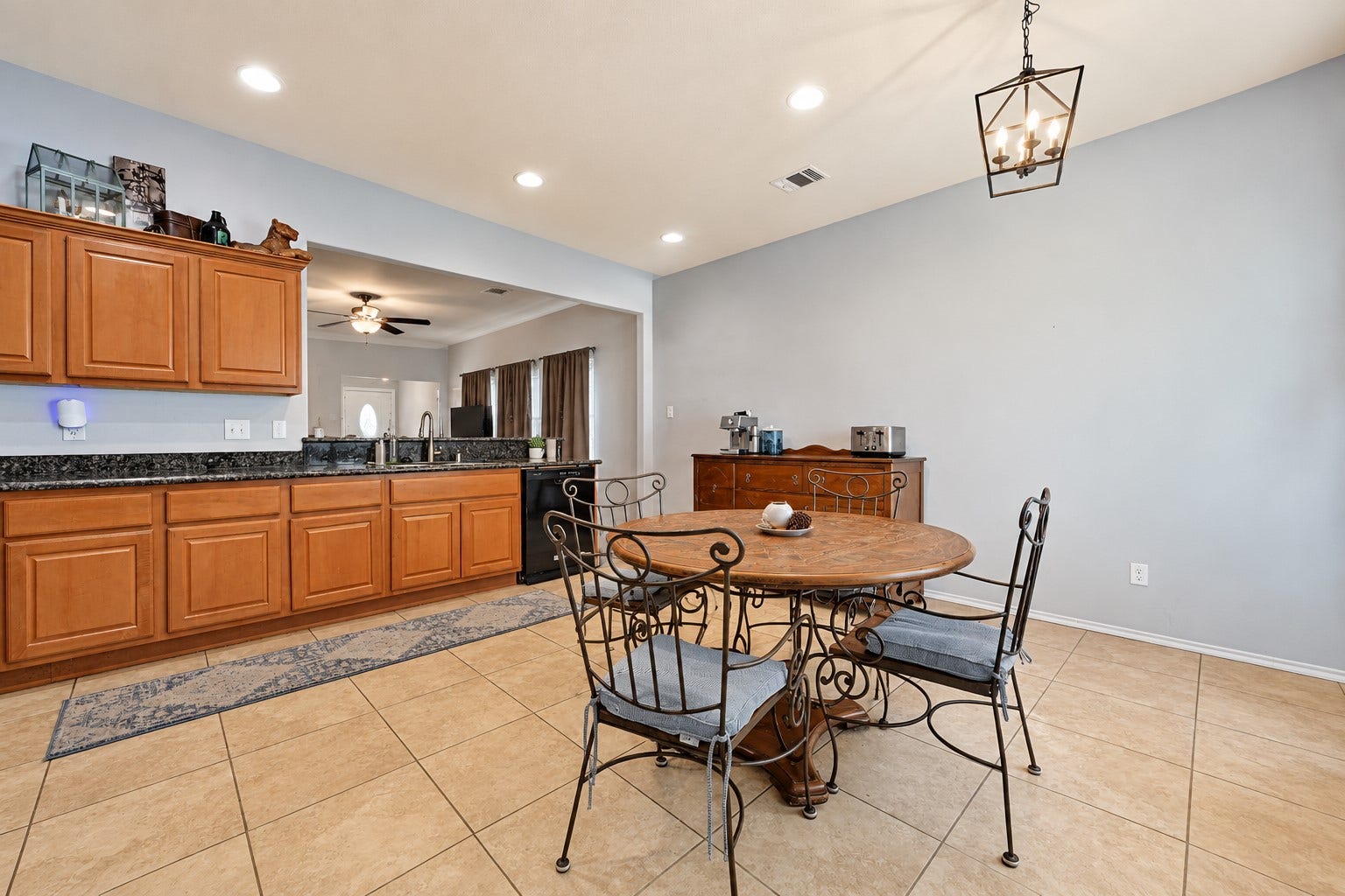 Spacious kitchen and dining area featuring warm wooden cabinetry, granite countertops, and a cozy breakfast nook under elegant lighting, perfect for family gatherings.